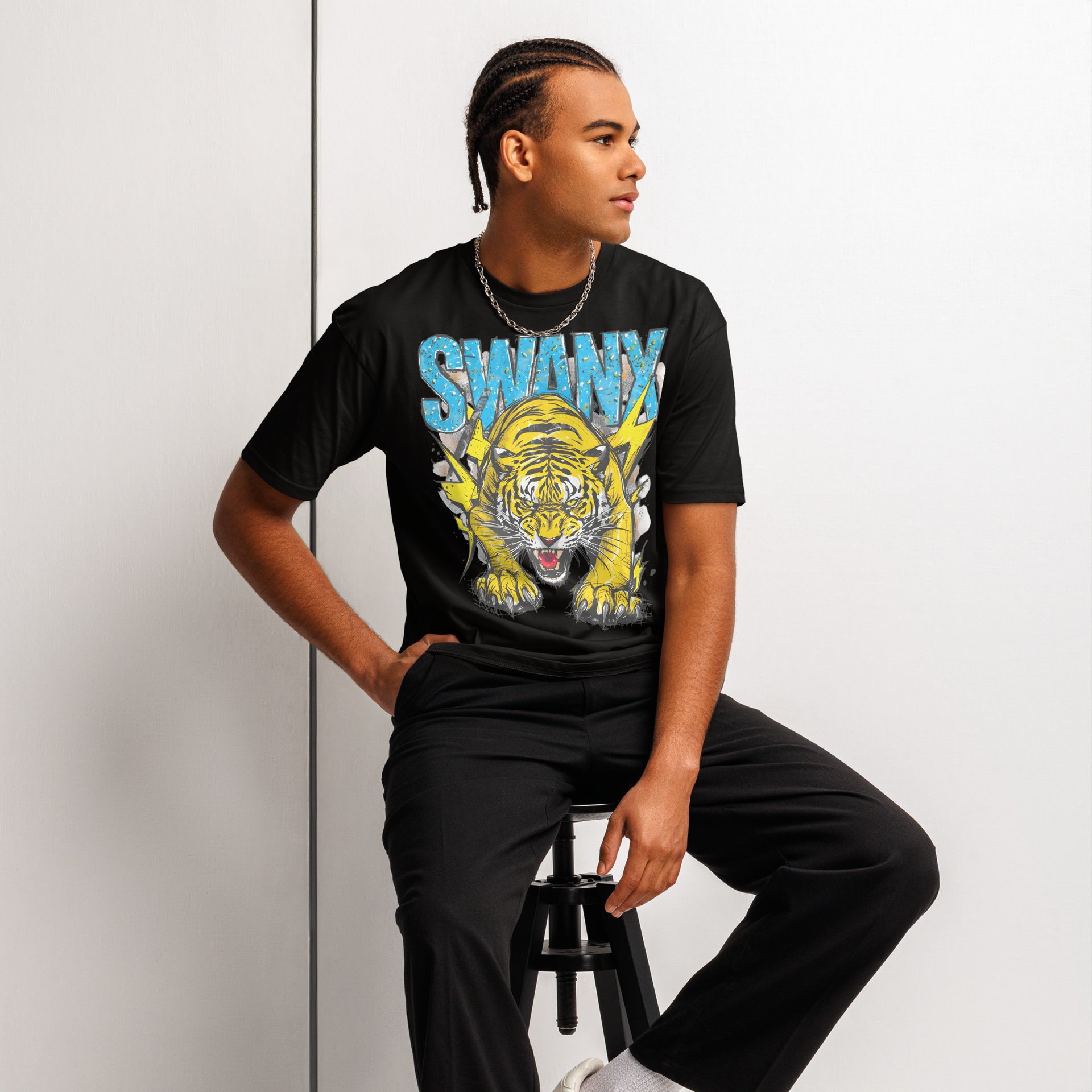 Young adult male model wearing a black graphic tee with a Tiger that says "SWANX". Industrial setting.