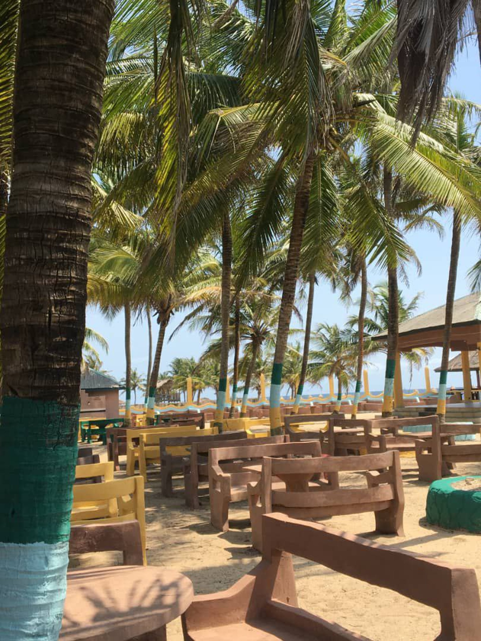 brown nipa hut near palm trees and body of water during daytime
