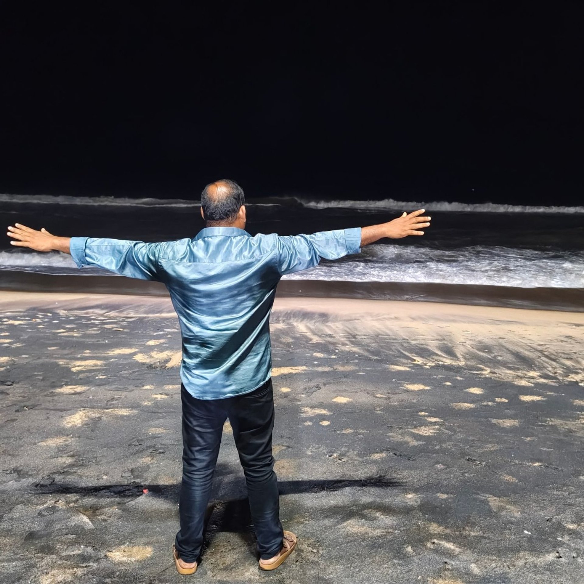 person standing on rock raising both hands