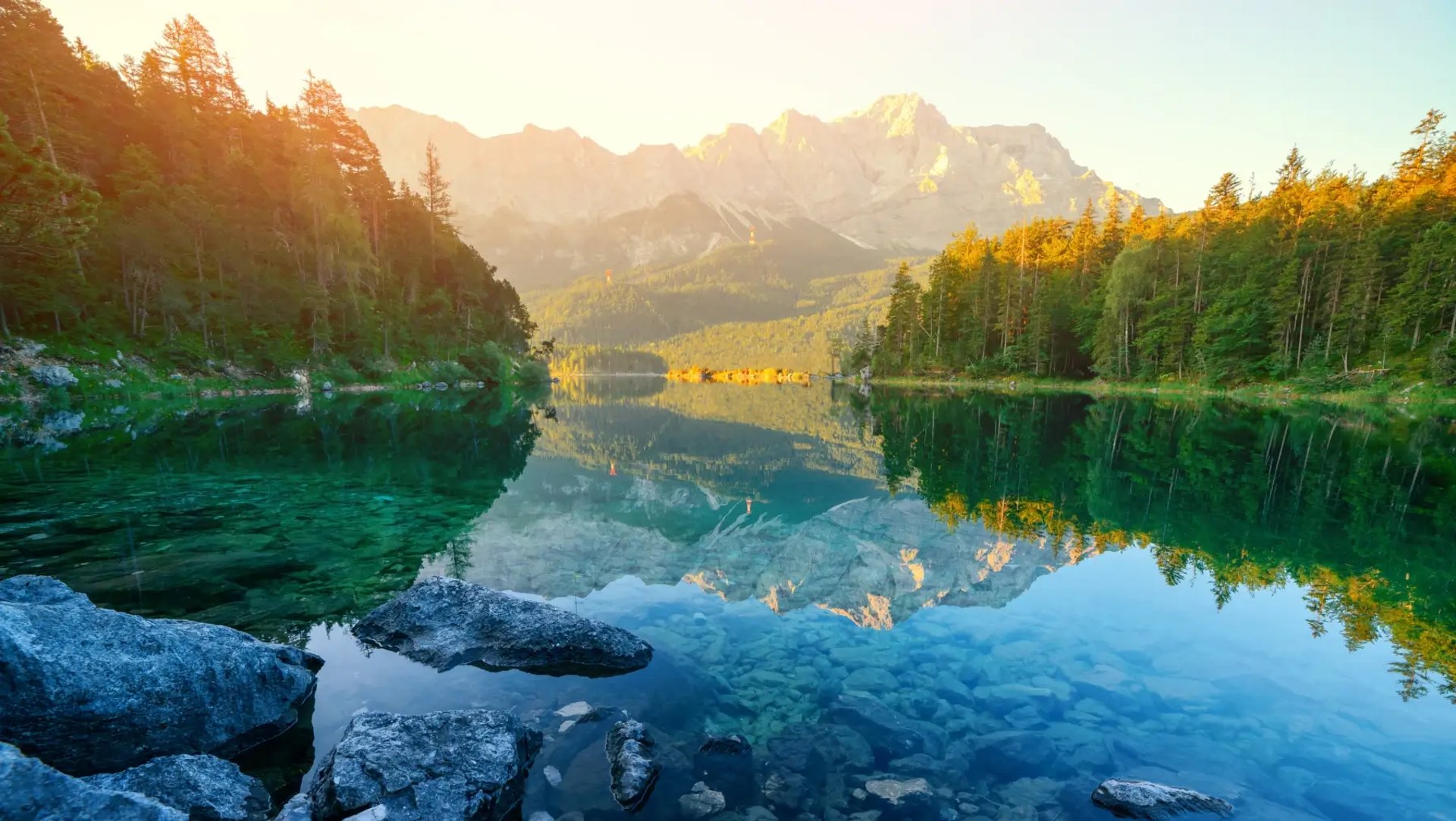 Lac entouré de pins, avec des montagnes en toile de fond, créant une scène harmonieuse et apaisante.