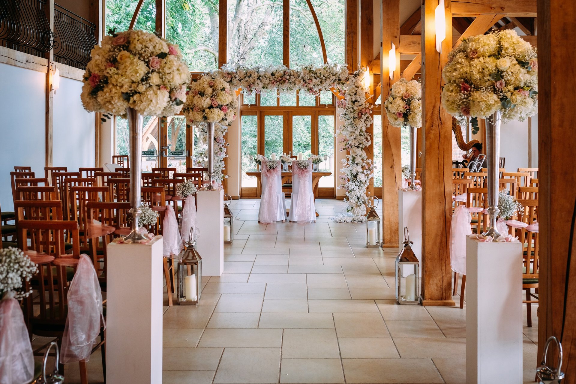 Elegant oak-framed ceremony space at Rivervale Barn, Surrey, with soft lighting and garden views. Wedding venue
