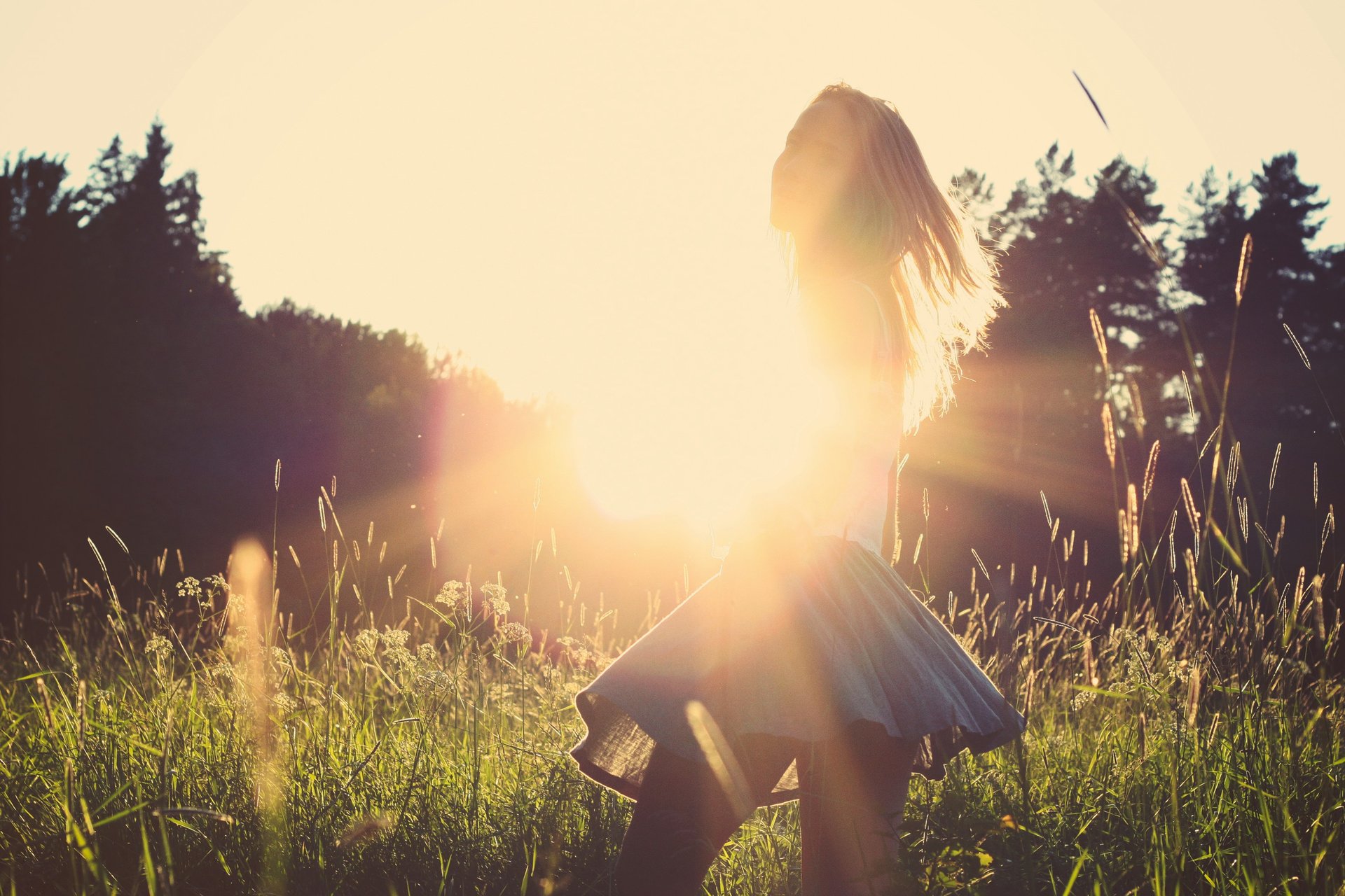 a person standing in a field with the sun setting in the background