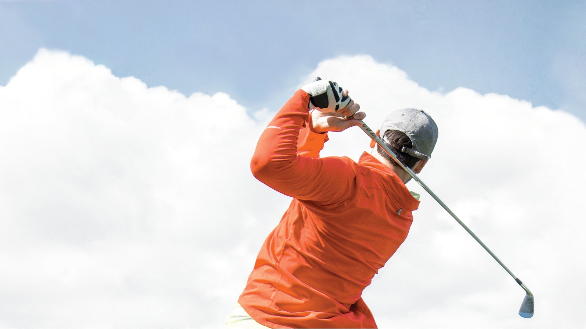 Photo of the back of a golfer's torso holding a golf club at back post-swing