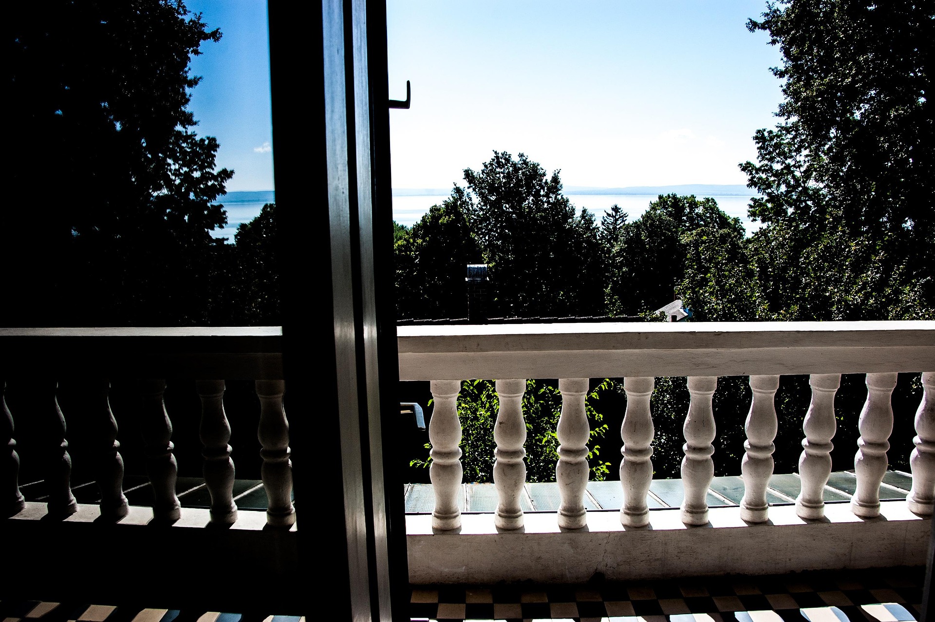 looking through sliding door out over trees with a lake in the background merging with the skyline
