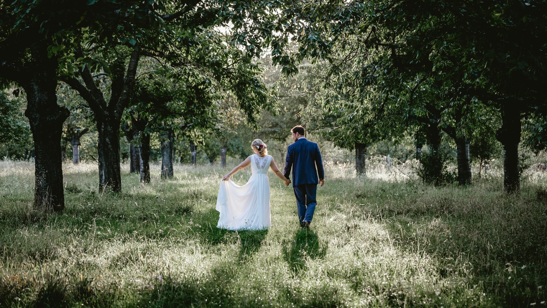 Mariés dans la forêt, mariée avec une robe blanche bohème, marié avec costume bleu, mariés de dos, mariage sur mesure