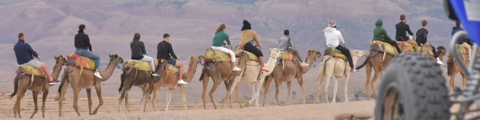 un banner que lleva turistas en agafay atlas montando camellos