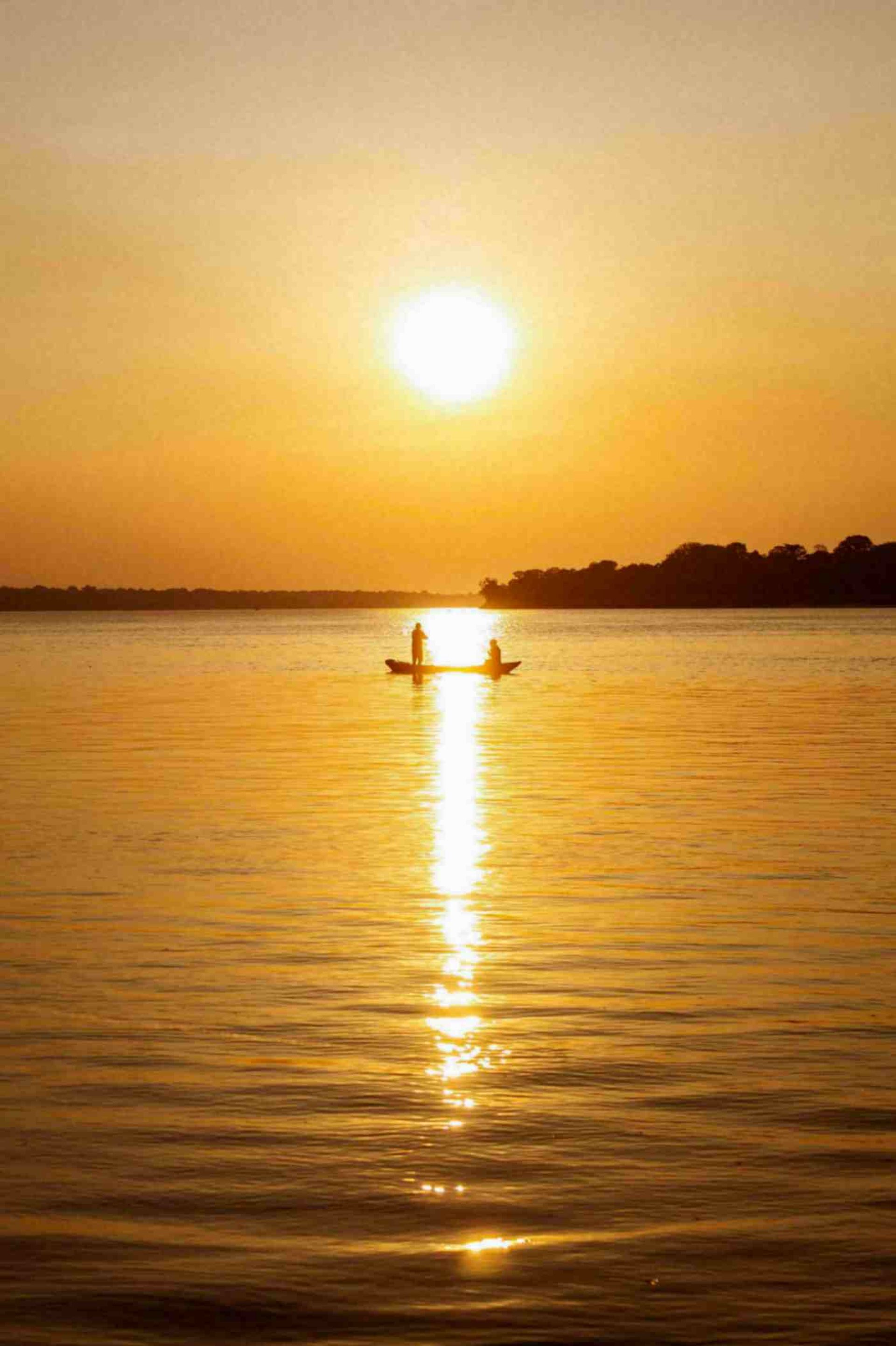 a person in a boat on a lake at sunset