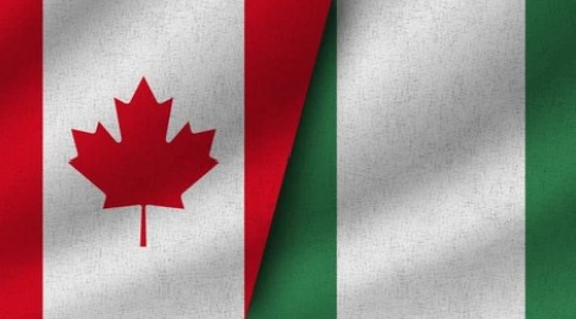 two american and canadian flags flying in the wind