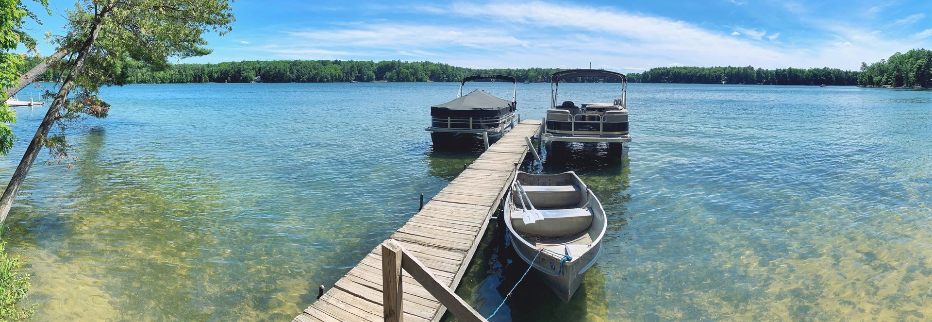 white and gray canoe beside gray wooden dock surrounded by body of water at daytime