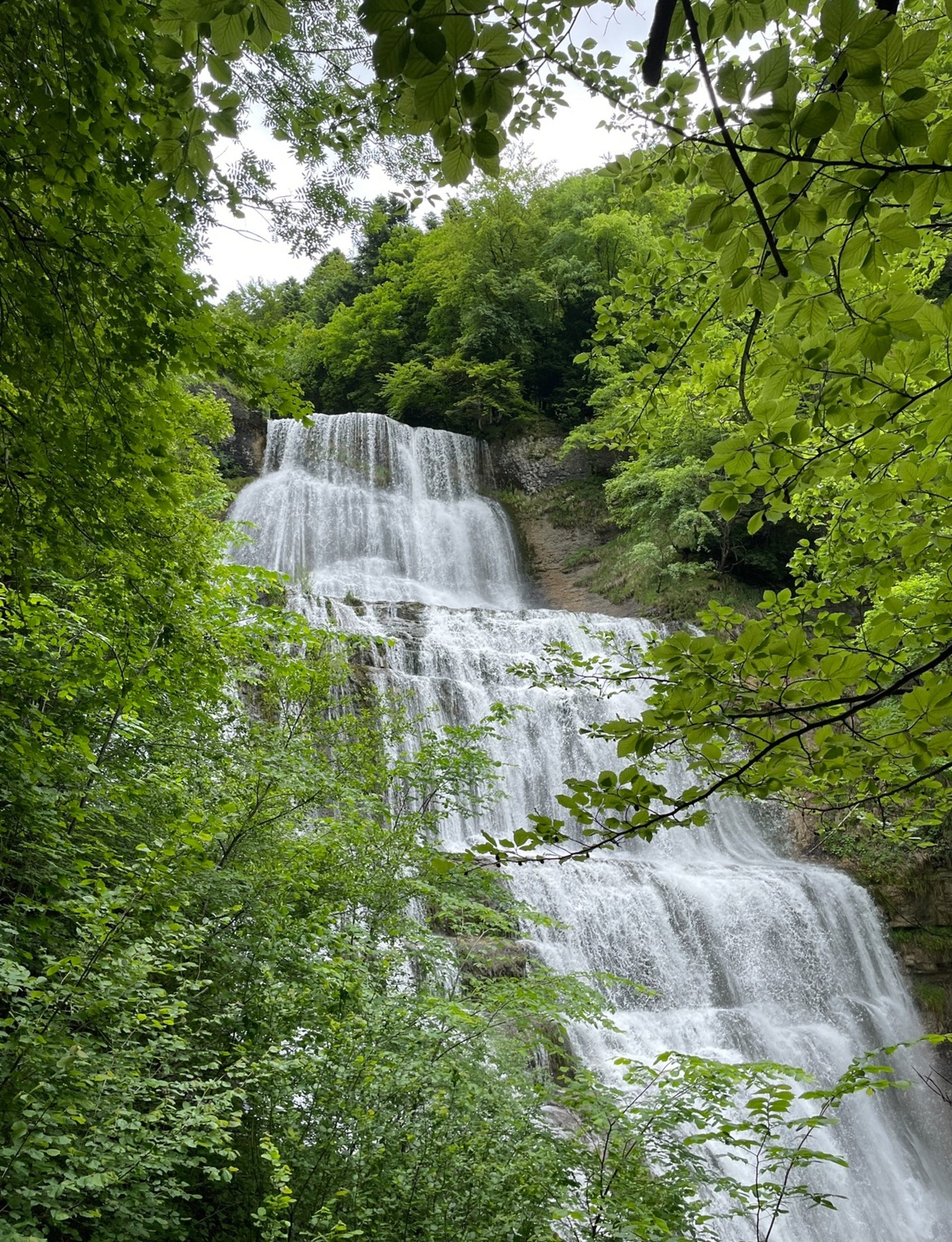 waterfalls on green and gray mountain under white clouds and blue sky during daytime