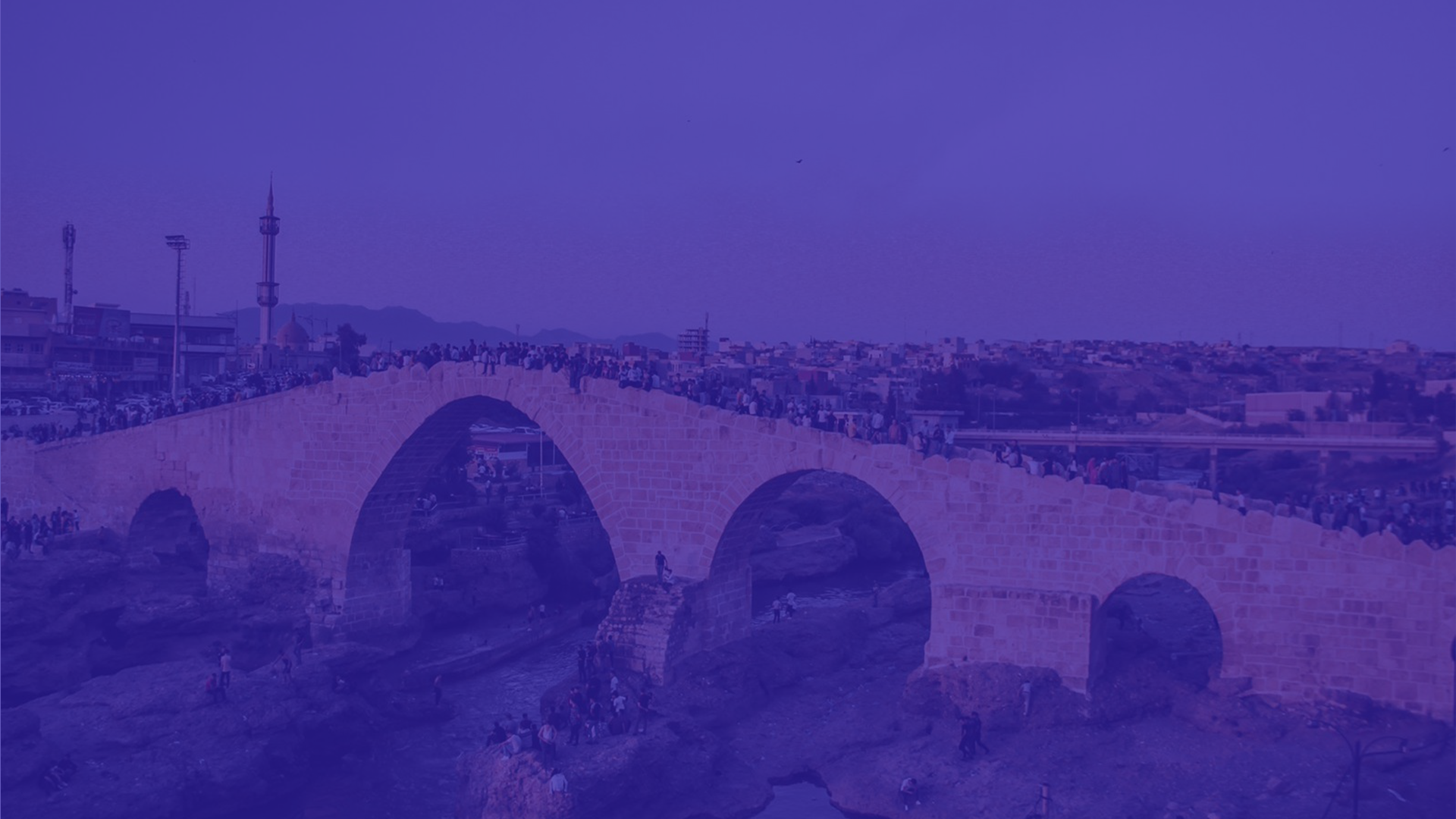 a bridge over a river with a city in the background
