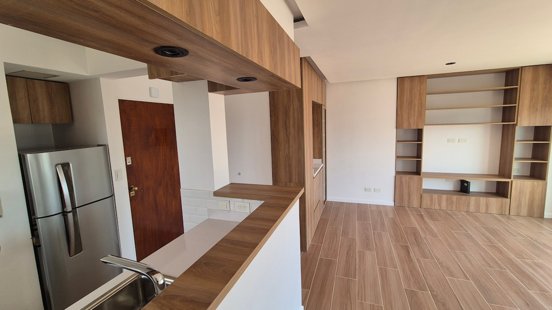 A remodeled kitchen and living room, with wooden floors and white walls