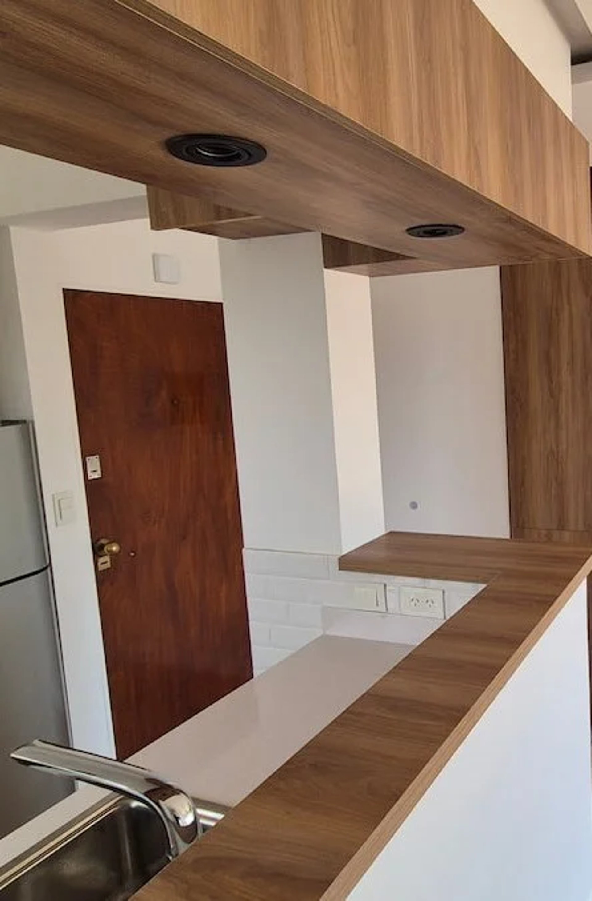 A remodeled kitchen and living room, with wooden floors and white walls