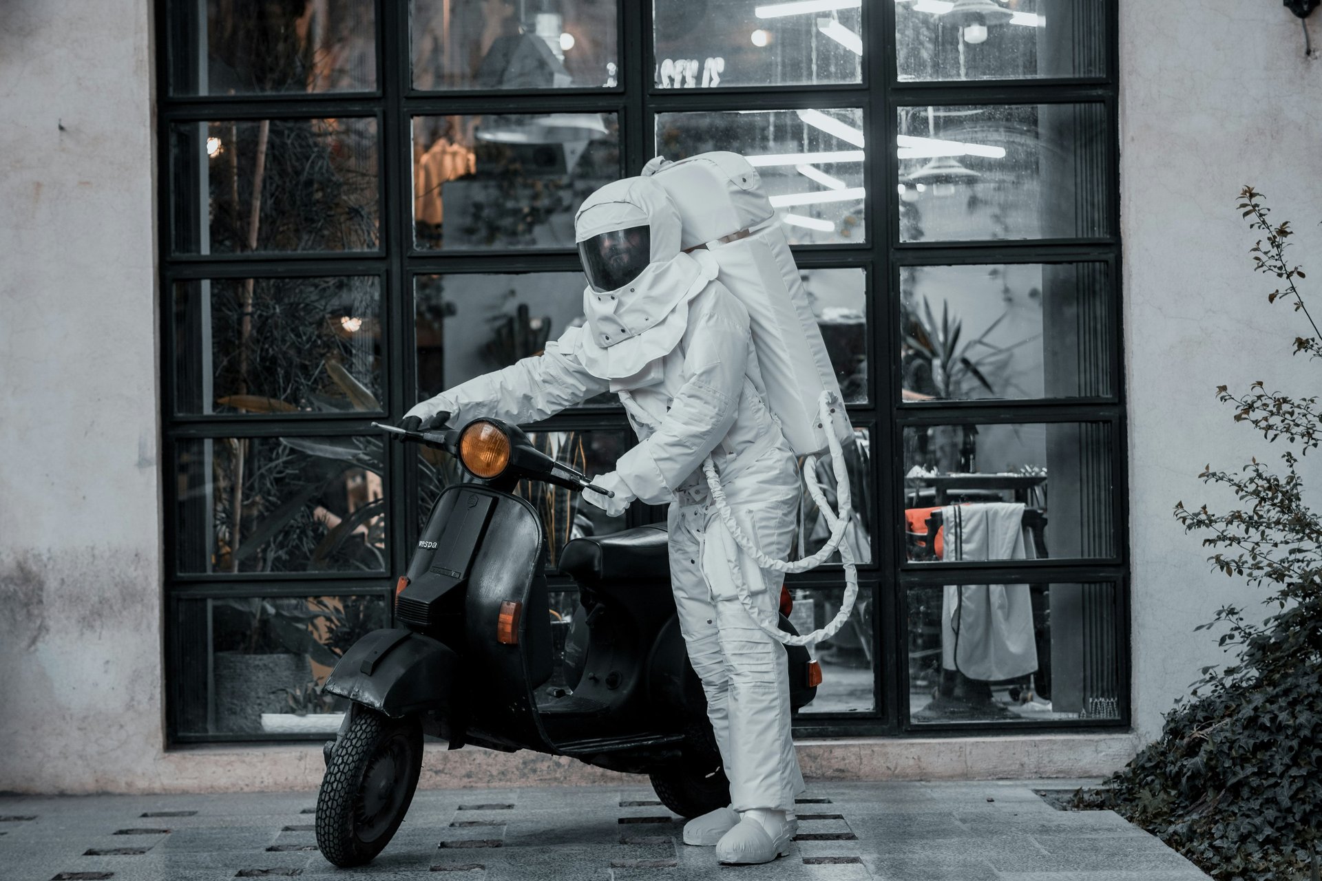 Motorcycle rider in space suit mounting a vespa scooter representing daily life challenges