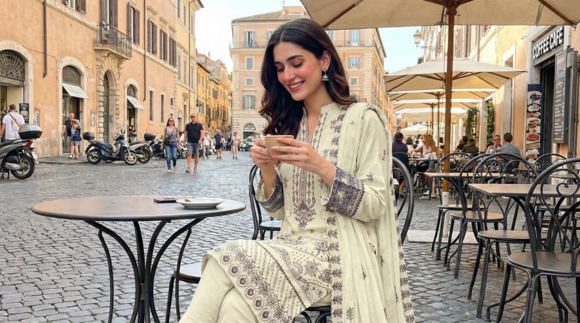 a woman in a brown dress standing next to a plant