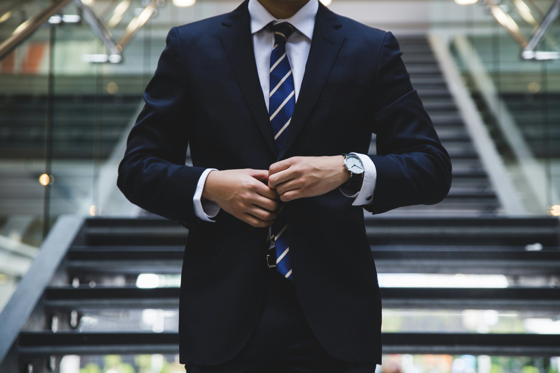man in black suit standing on top of building looking at city buildings during daytime