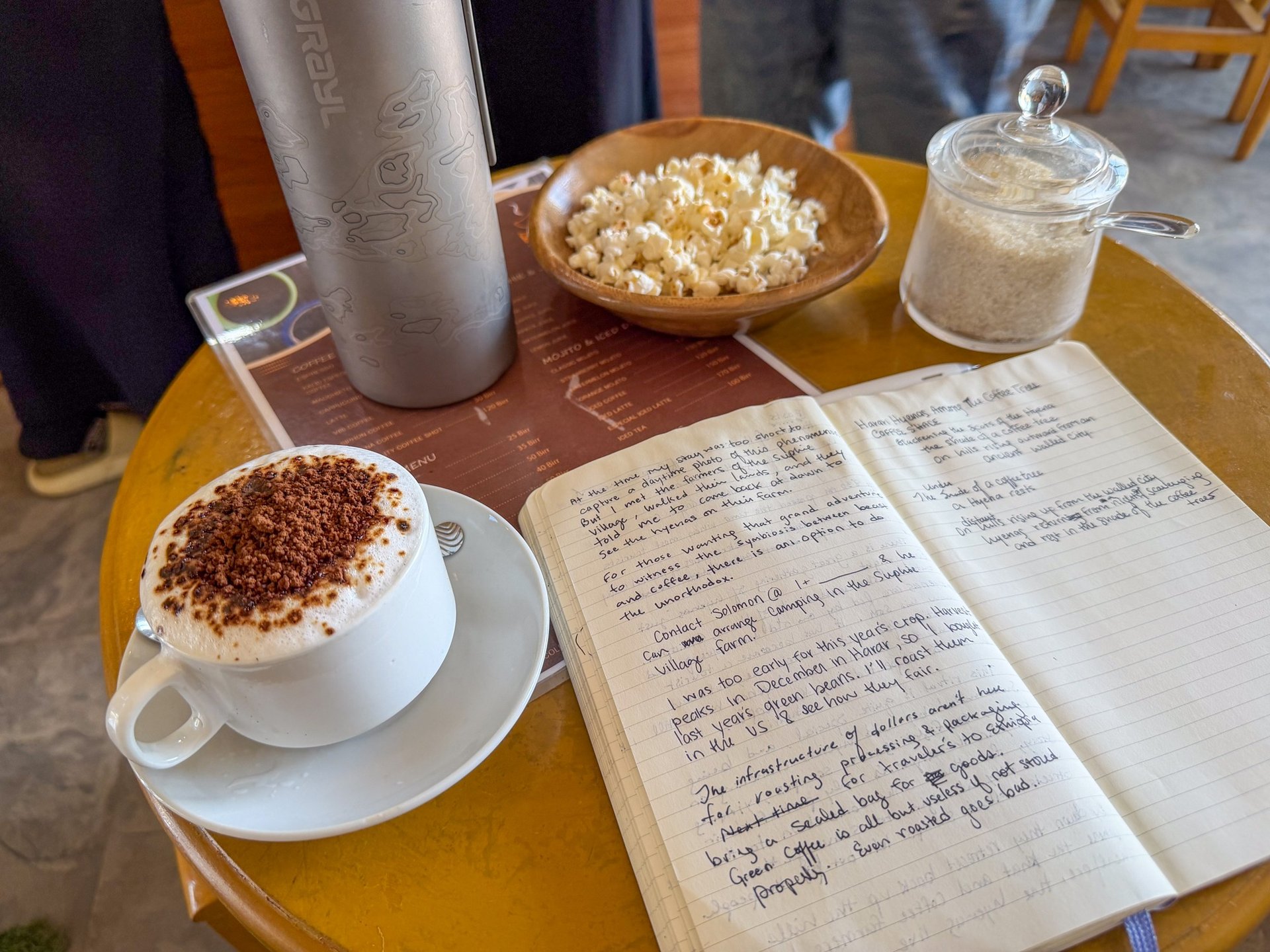 a cup of coffee next to a sack of coffee beans