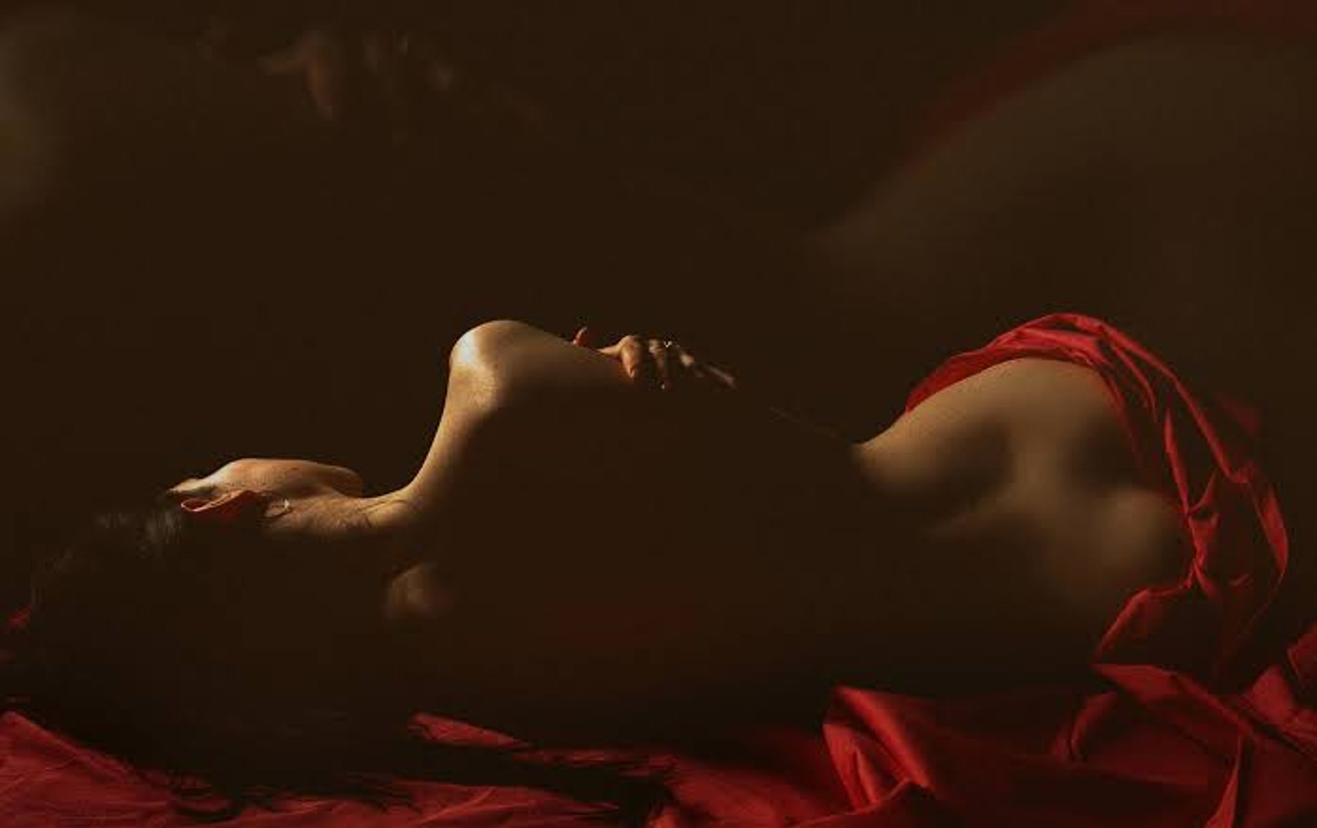 woman in black brassiere lying on blue and white bed