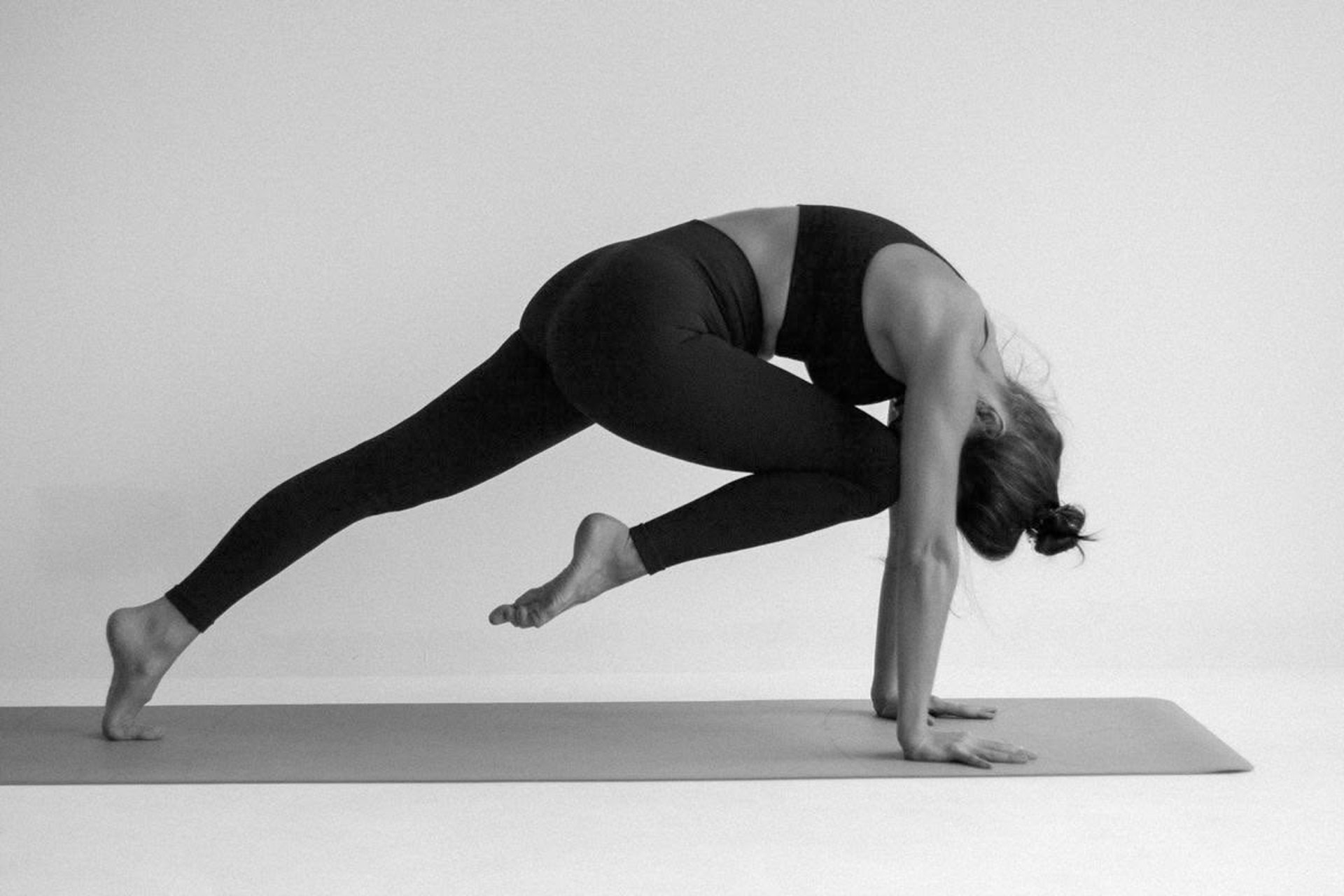woman in white tank top bending her body on floor