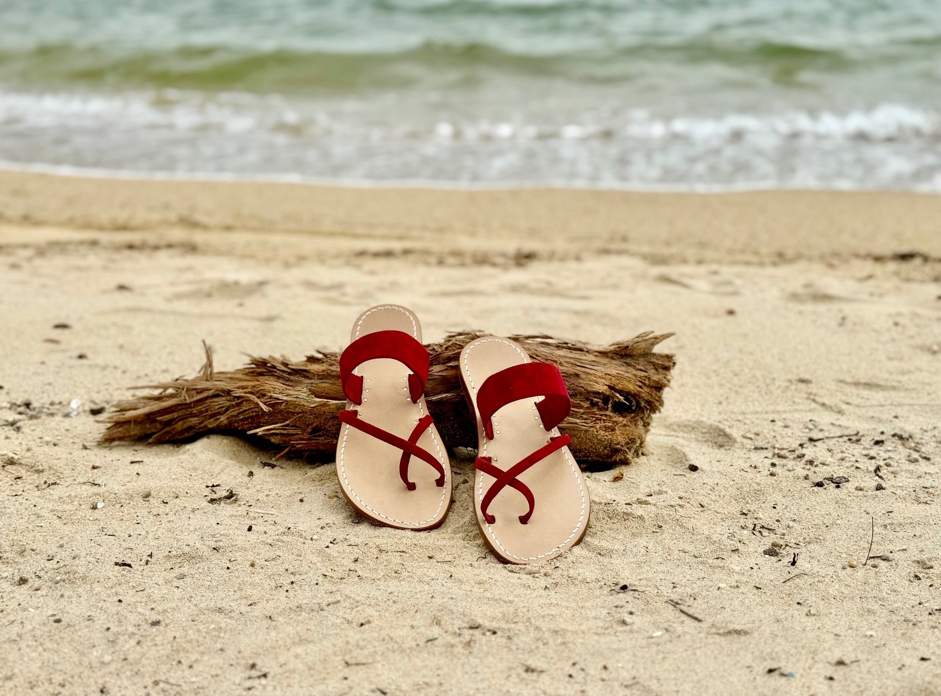 A pair of pink sandals sitting on top of a sandy beach
