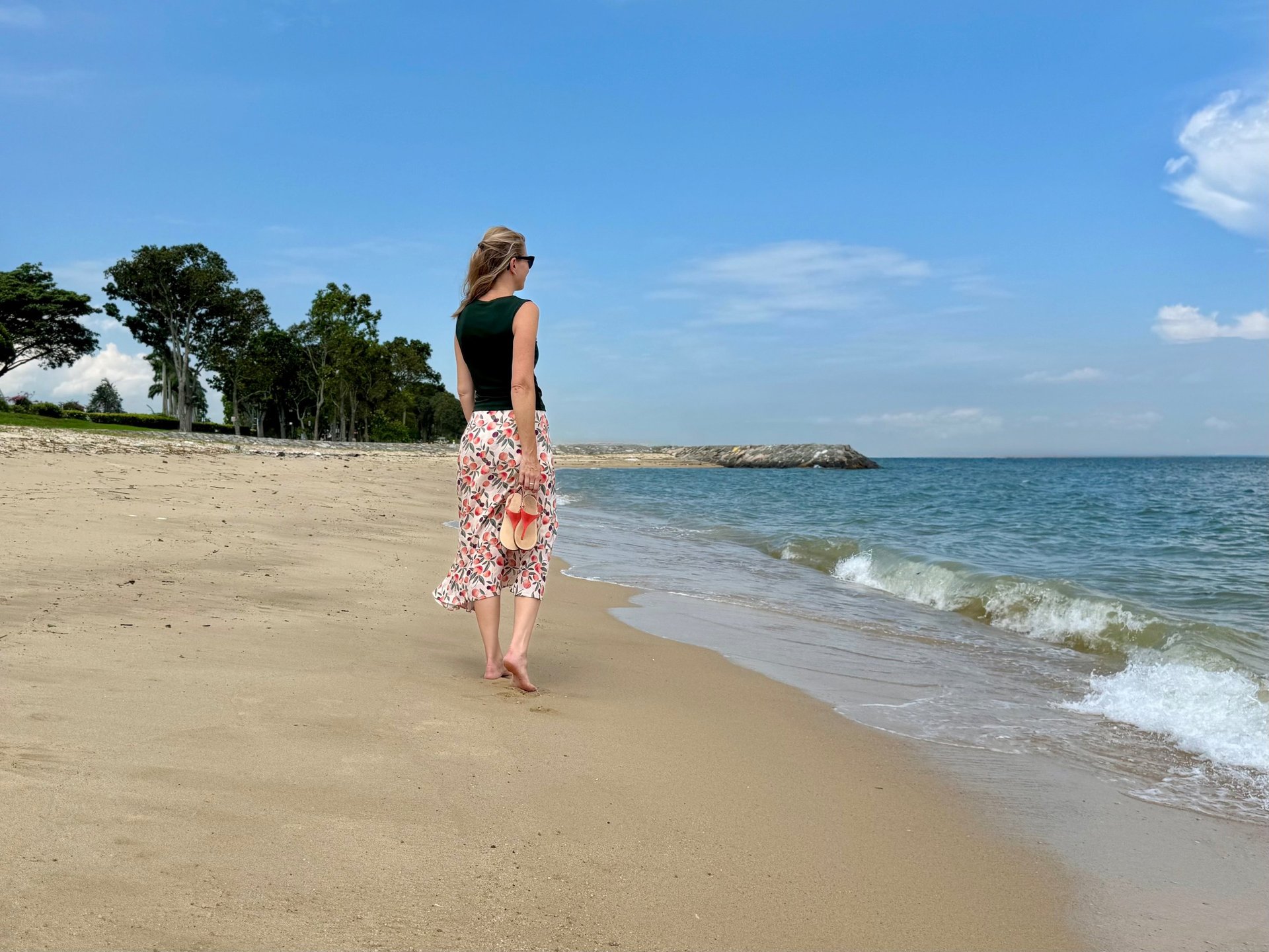 woman wearing brown sun hat walking on the seashore