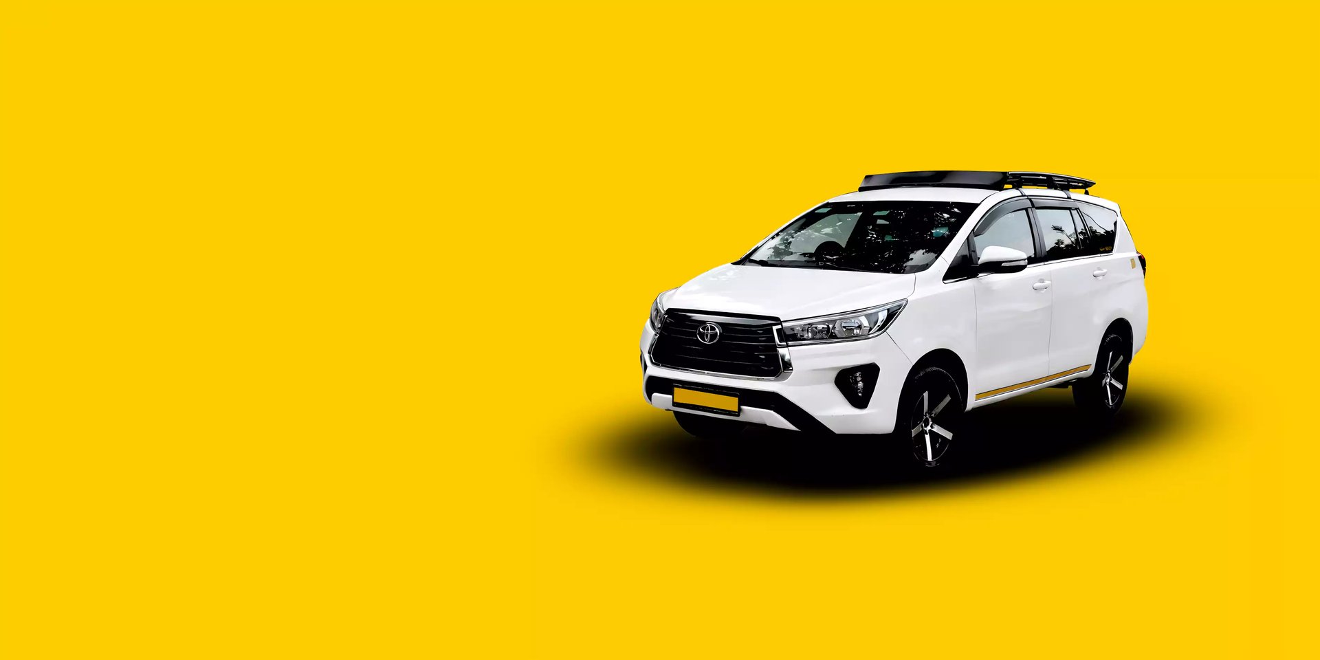 White Toyota Innova Crysta taxi service with a black roof carrier on a bright yellow background