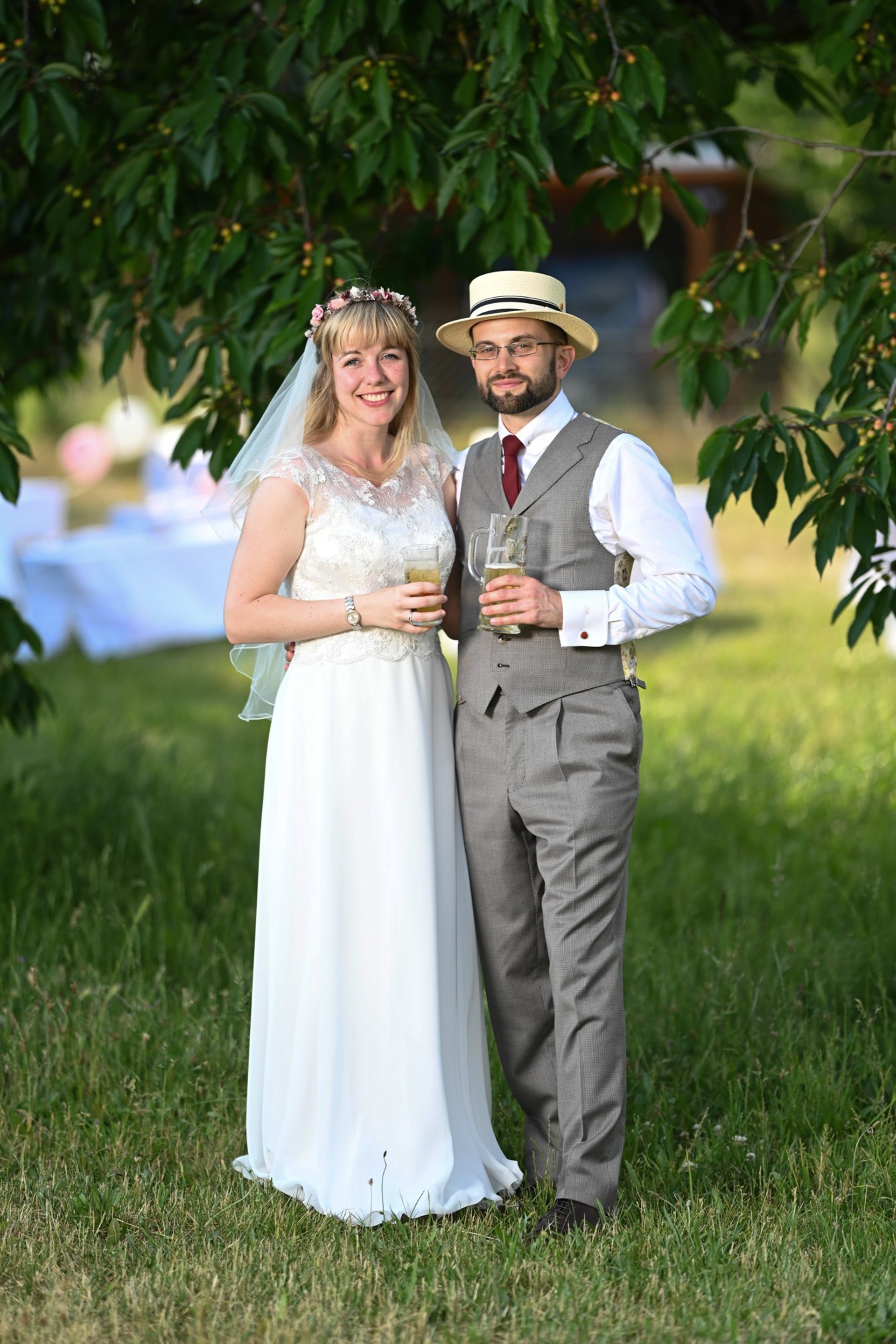 Brautpaar steht unter einem Baum und stößt an – Hochzeitsfotograf Oranienburg