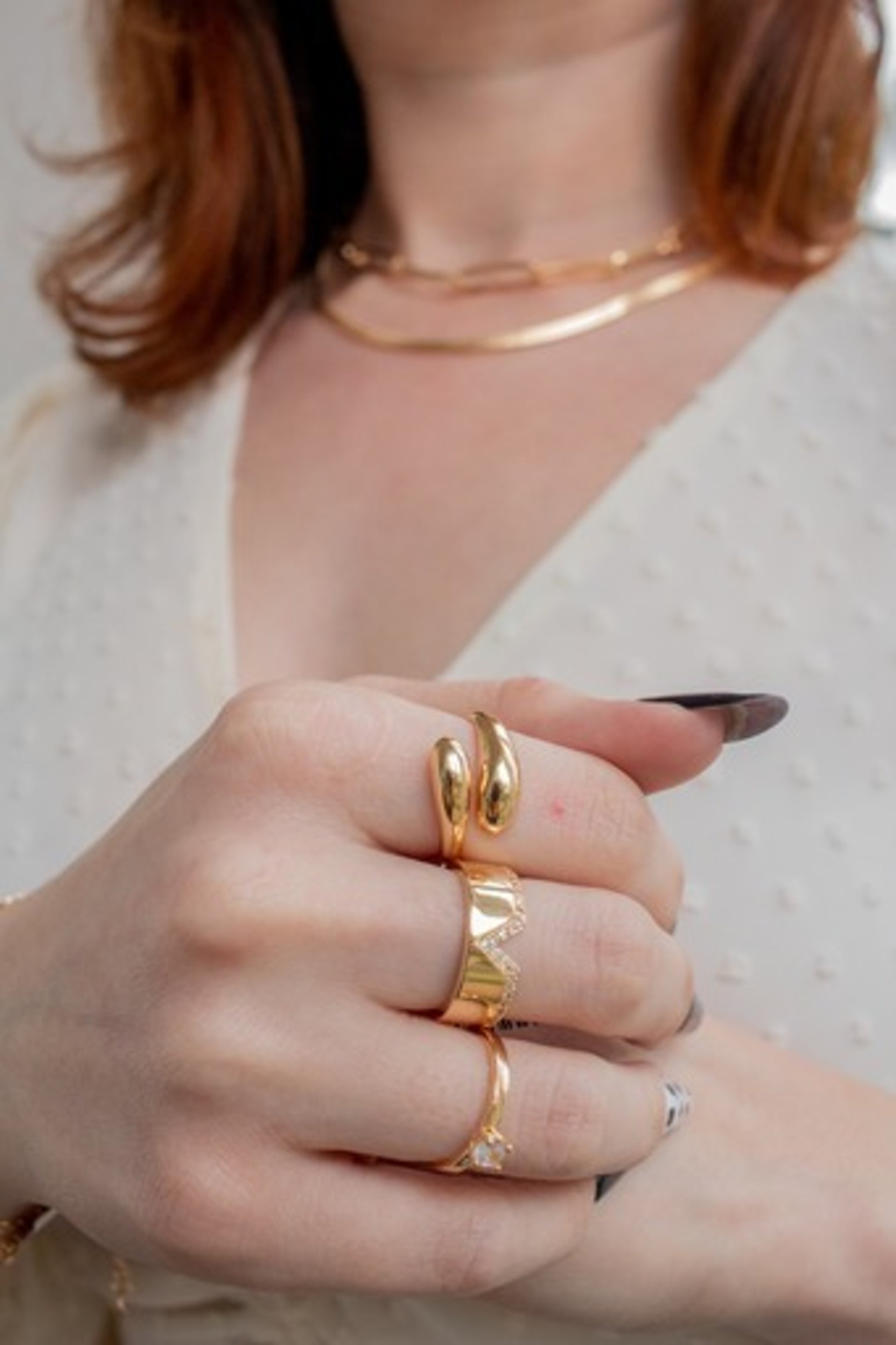 woman in black long sleeve shirt and blue denim jeans sitting on white concrete wall