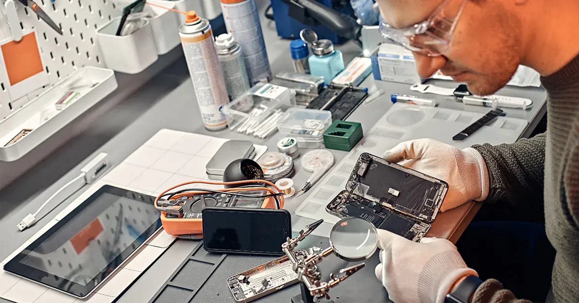 person repairing smartphones under a lighted table