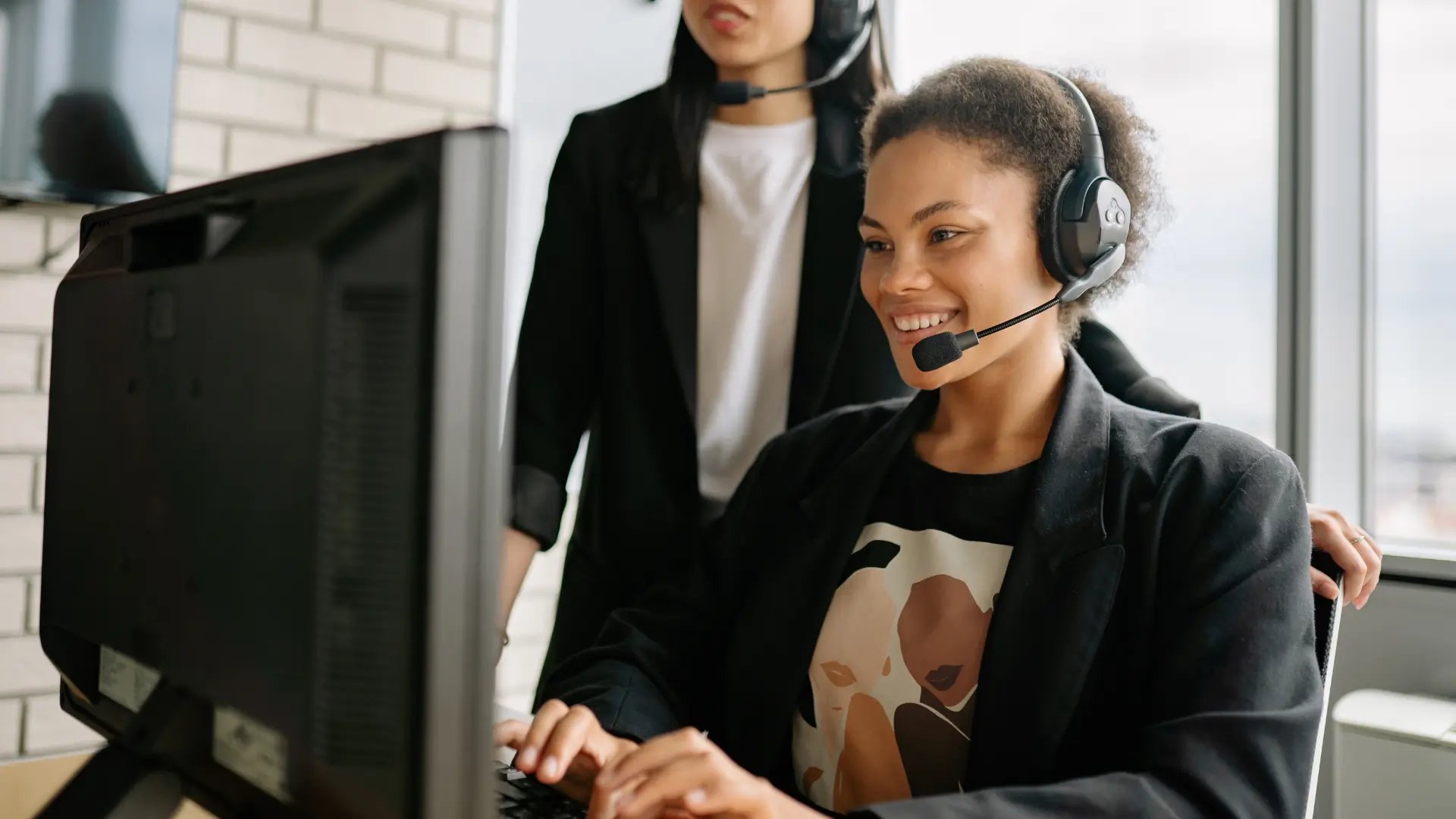 A smiling woman wearing a headset at a computer.