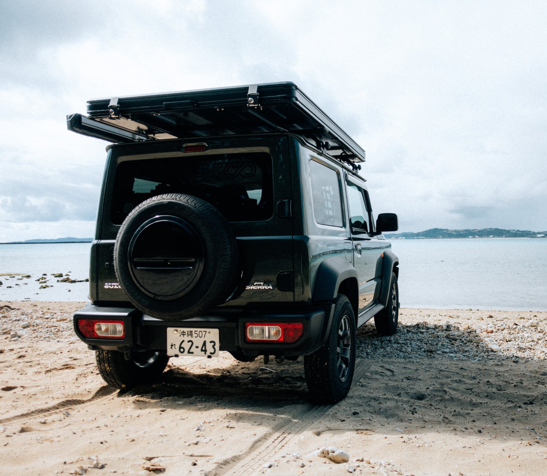 Black and white photo of a Suzuki Jimny with a rooftop tent under a starry night sky in Okinawa | Evertrail Okinawa Camping