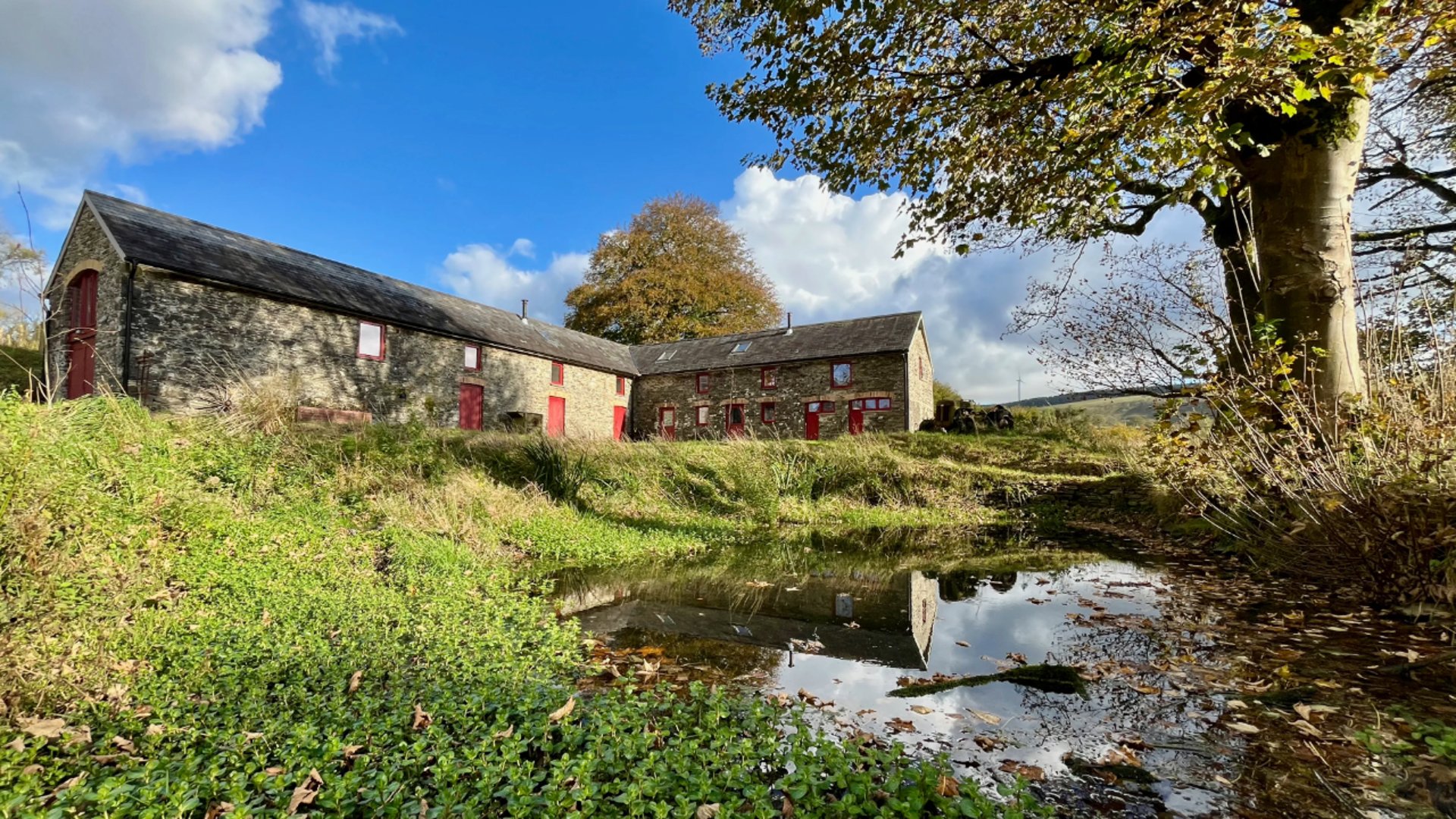 a view of the barns with pond in the foreground