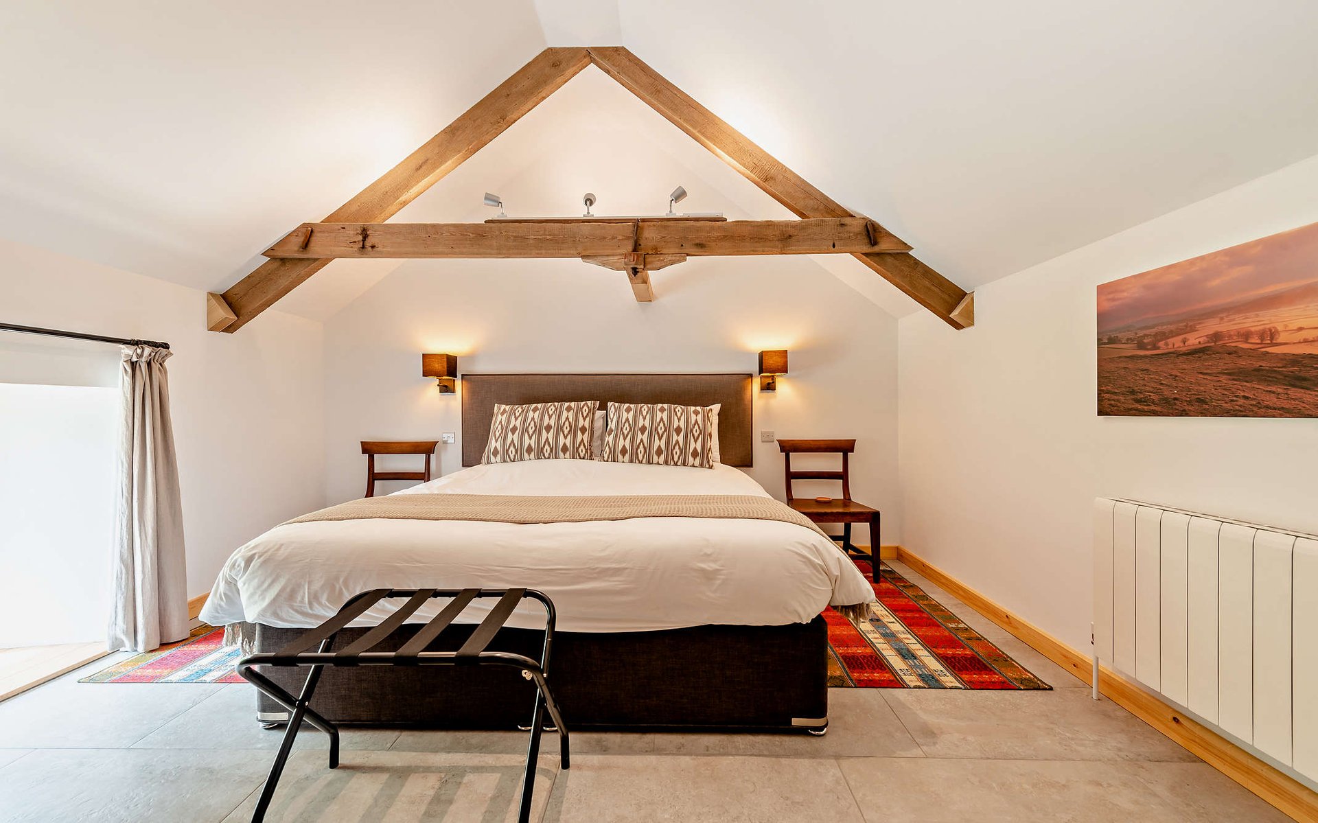 a large bedroom with wooden beams and wall lights