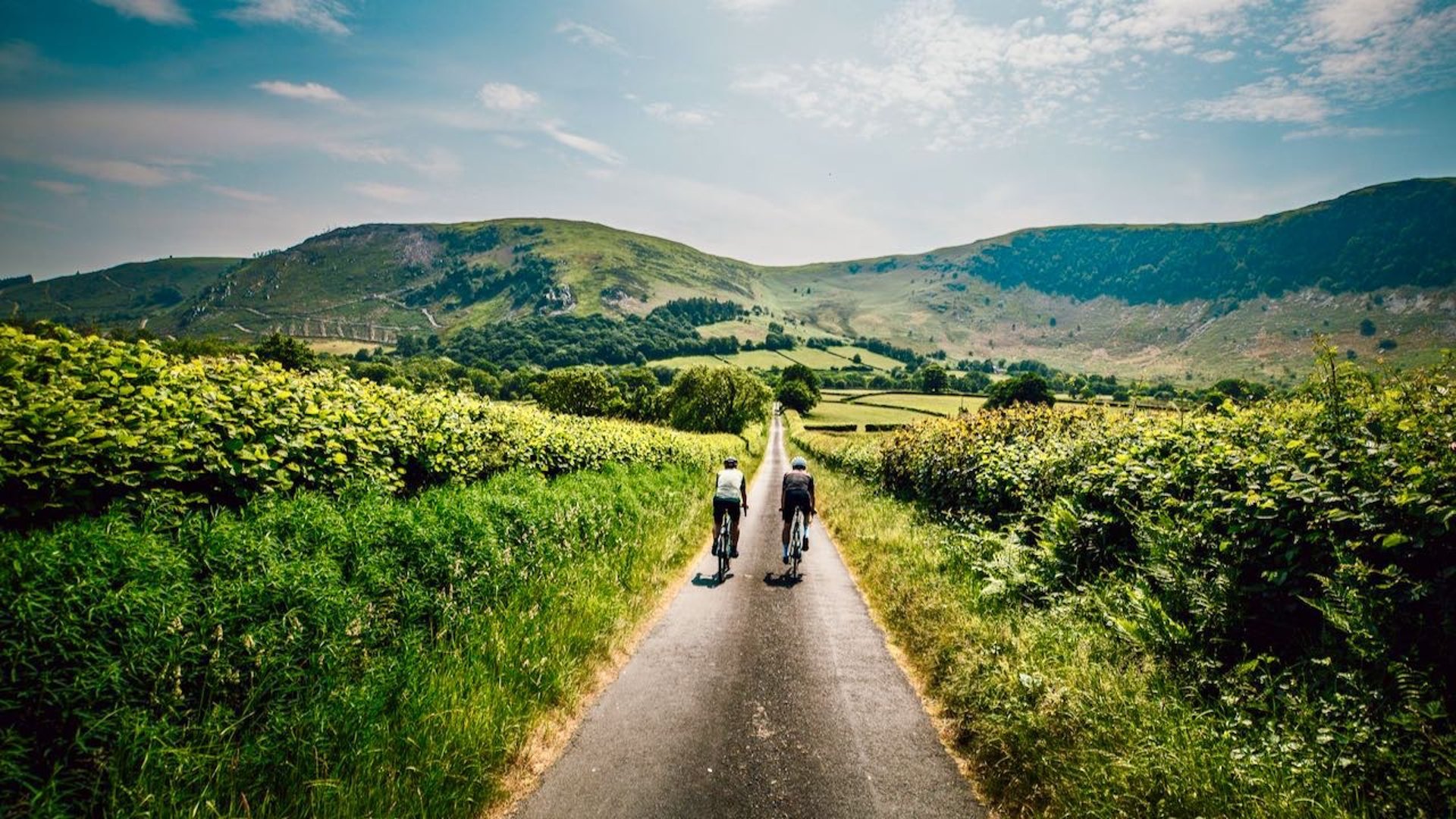 two cyclists in a countryside lane with the hills behind