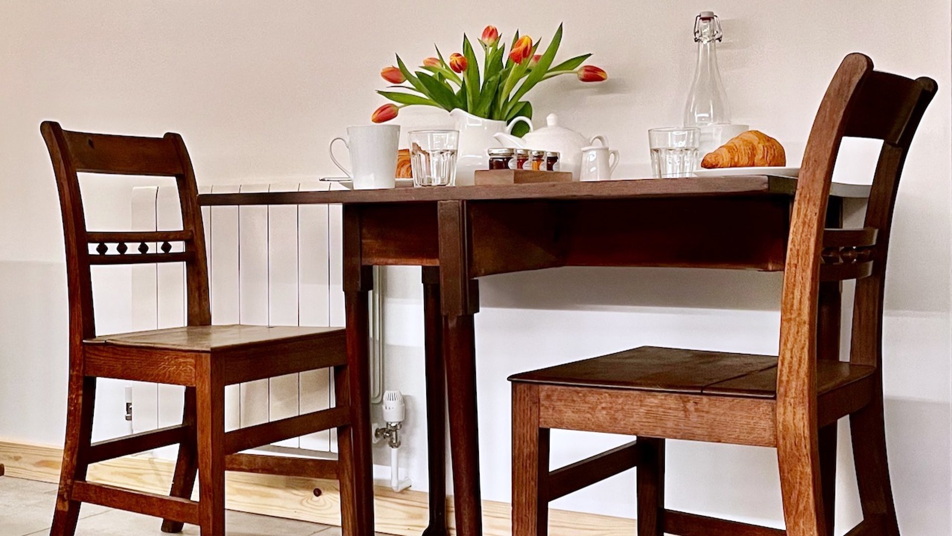 some antique chairs and a table with a jug of tulips