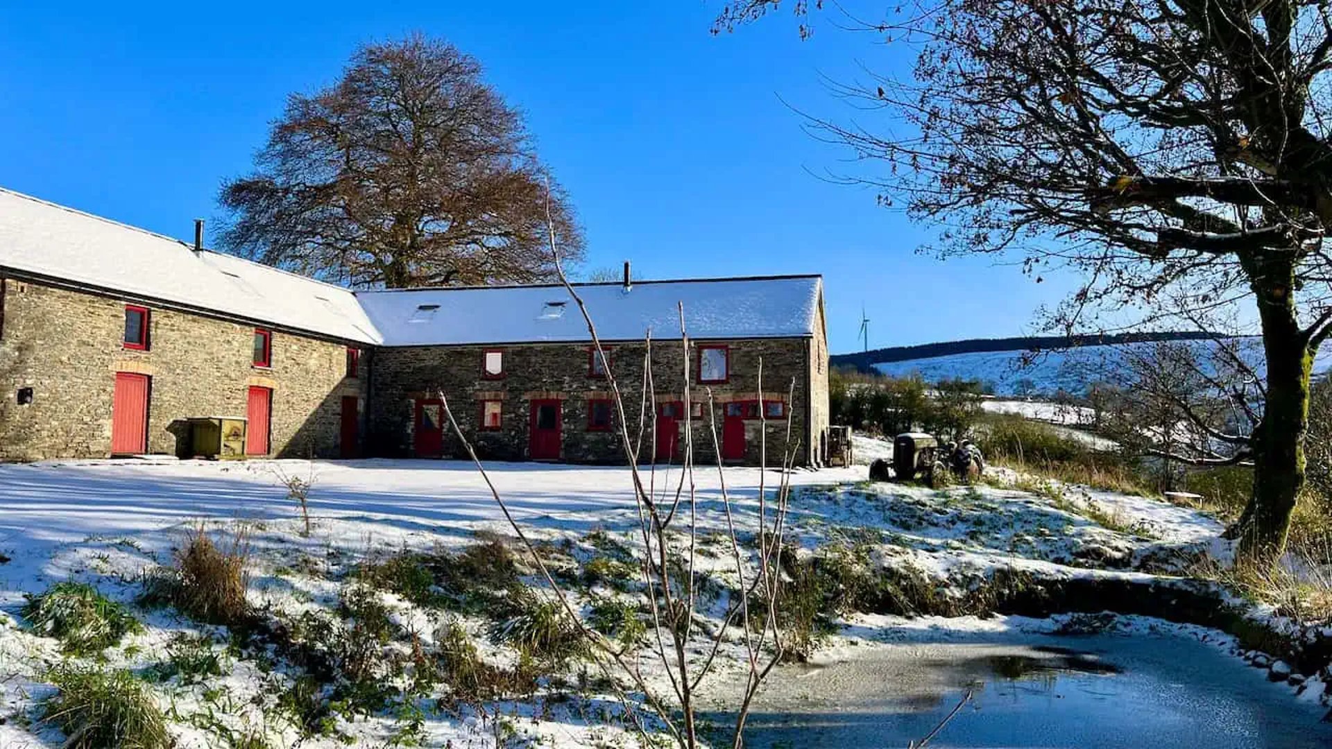 a beautiful barn with a large pond in front in the winter sunshine