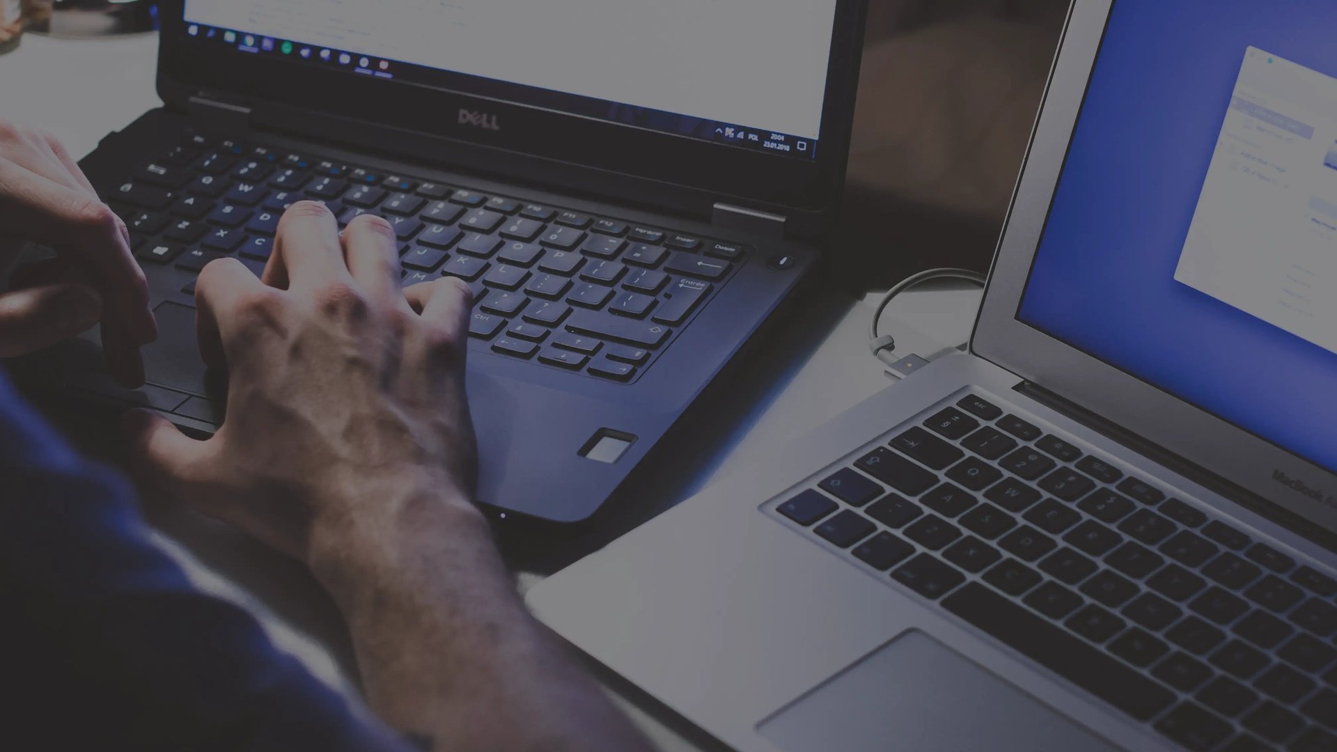 A man working on two laptops (photo by freestocks on Unsplash)