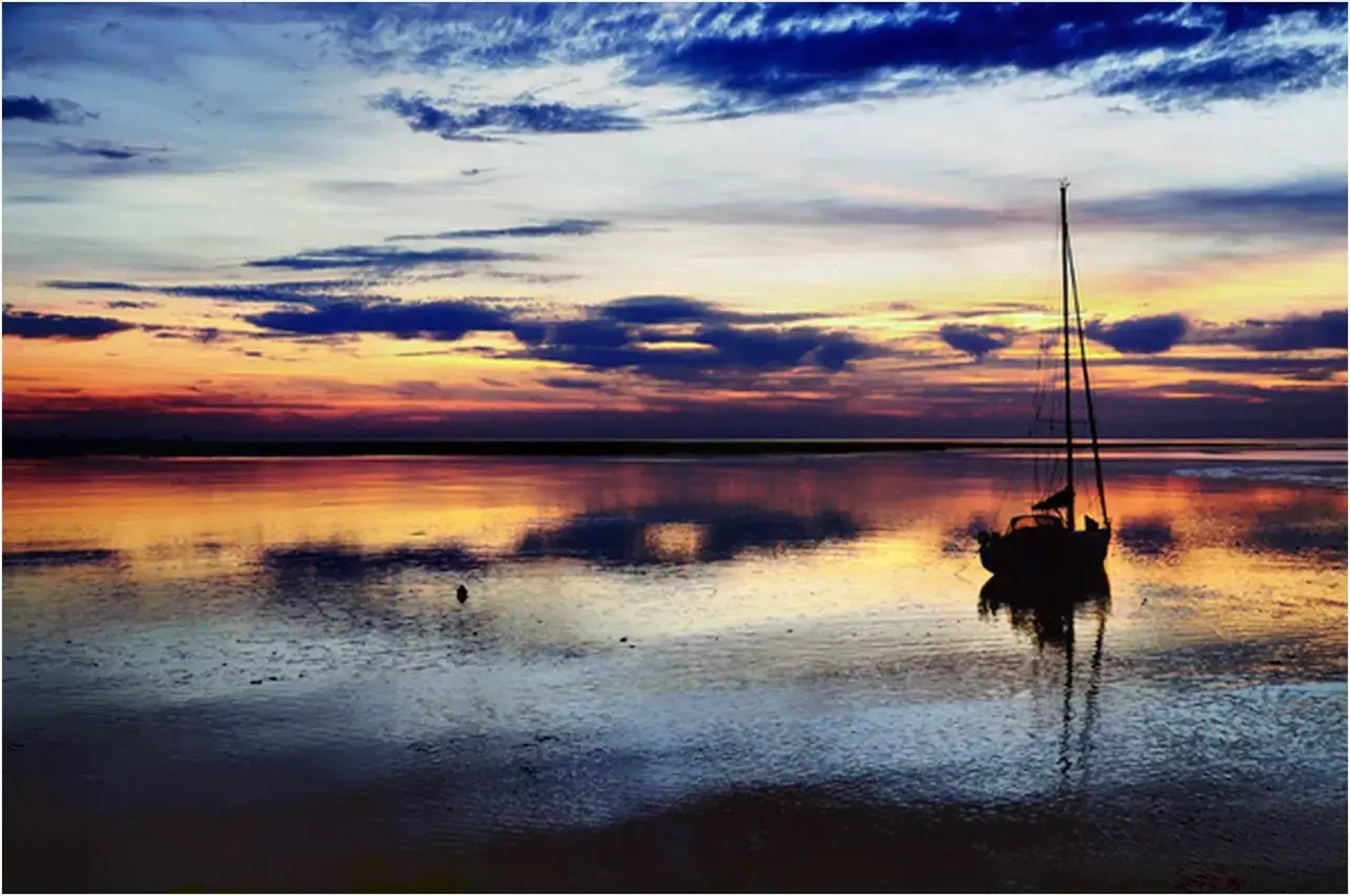 Voilier au mouillage, mer calme sous un coucher de soleil aux couleurs vives