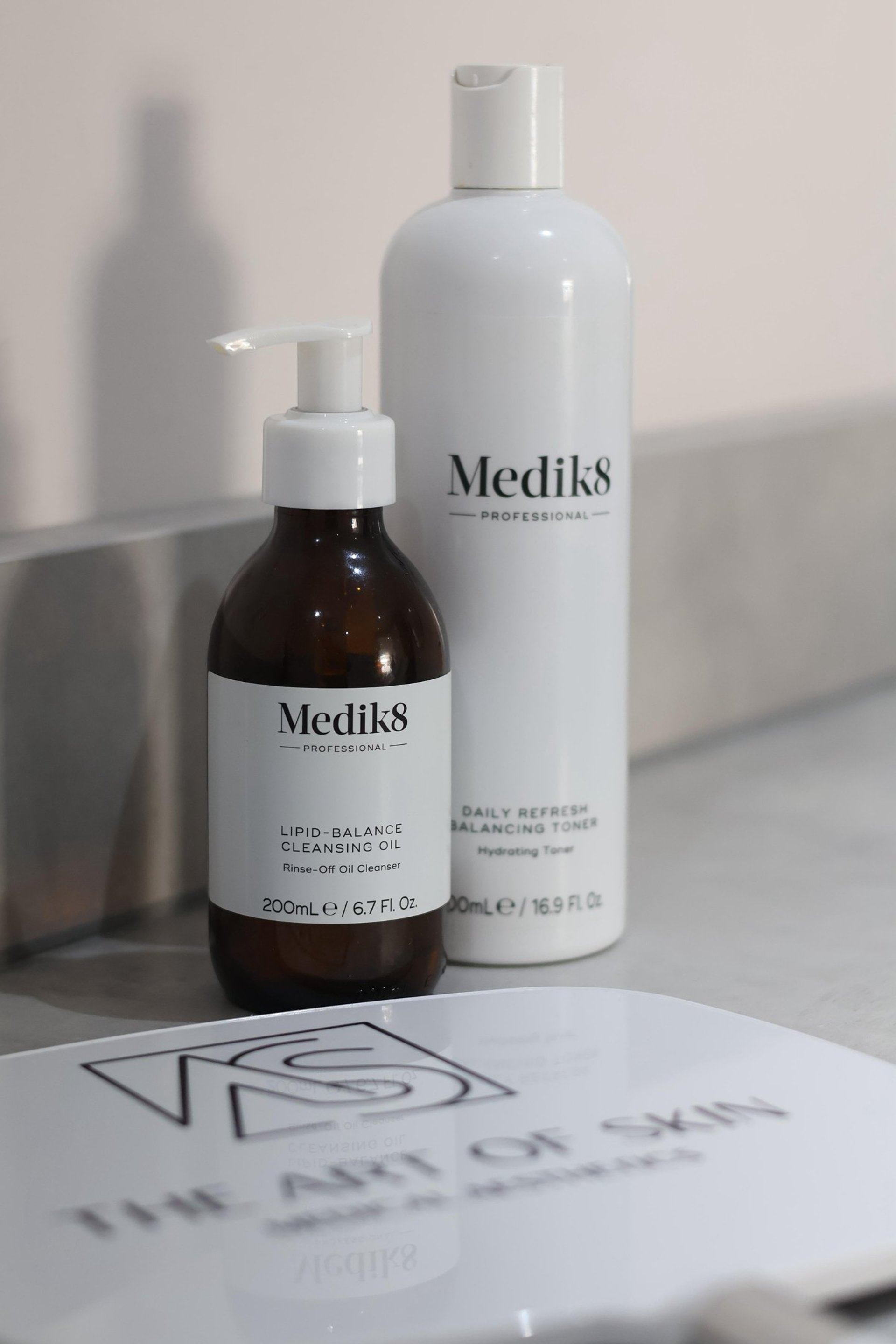 three bottles of lotion sitting on a table next to a potted plant