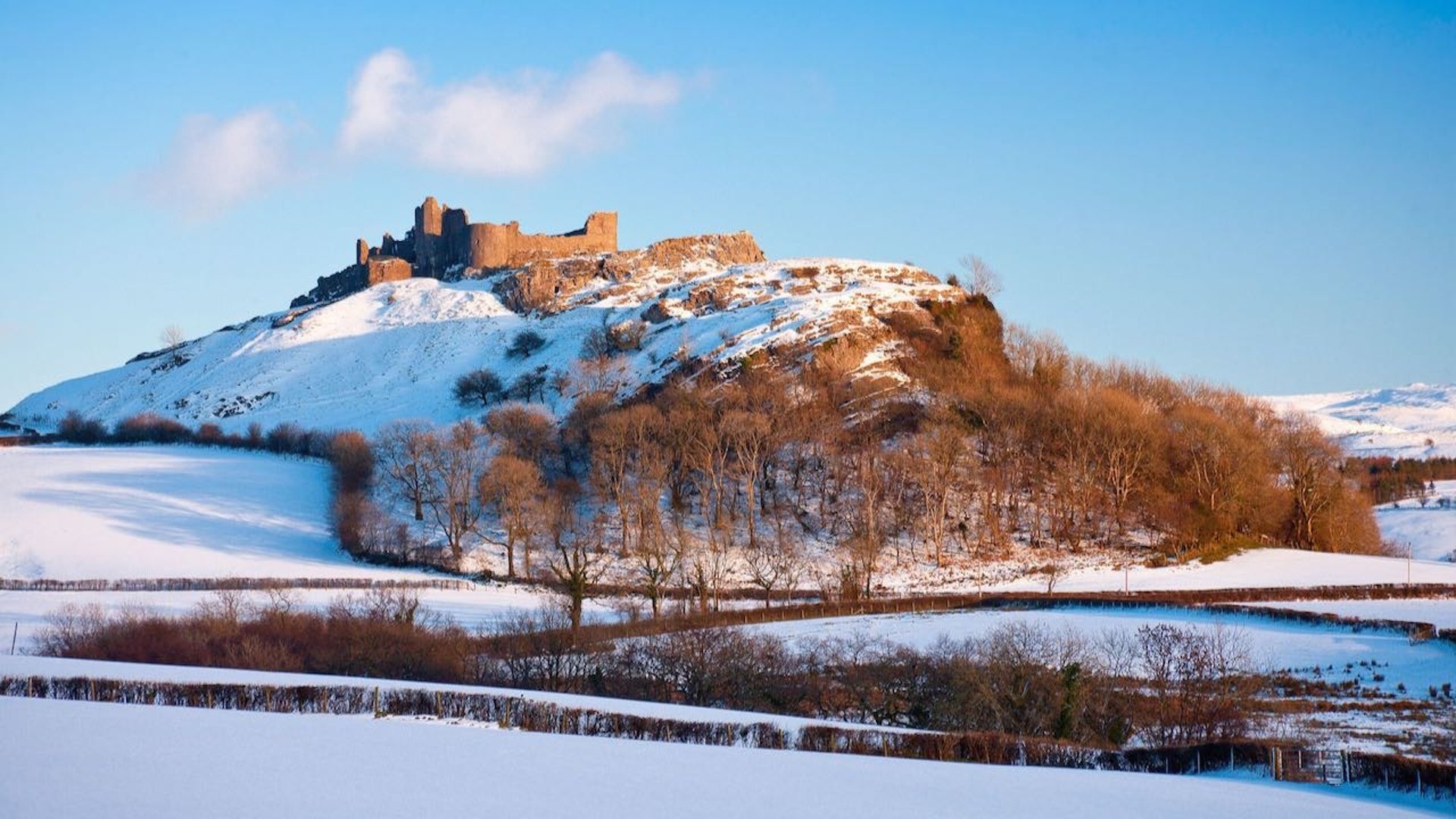 a castle on top of a hill in bright winter sunlight with snow on the ground