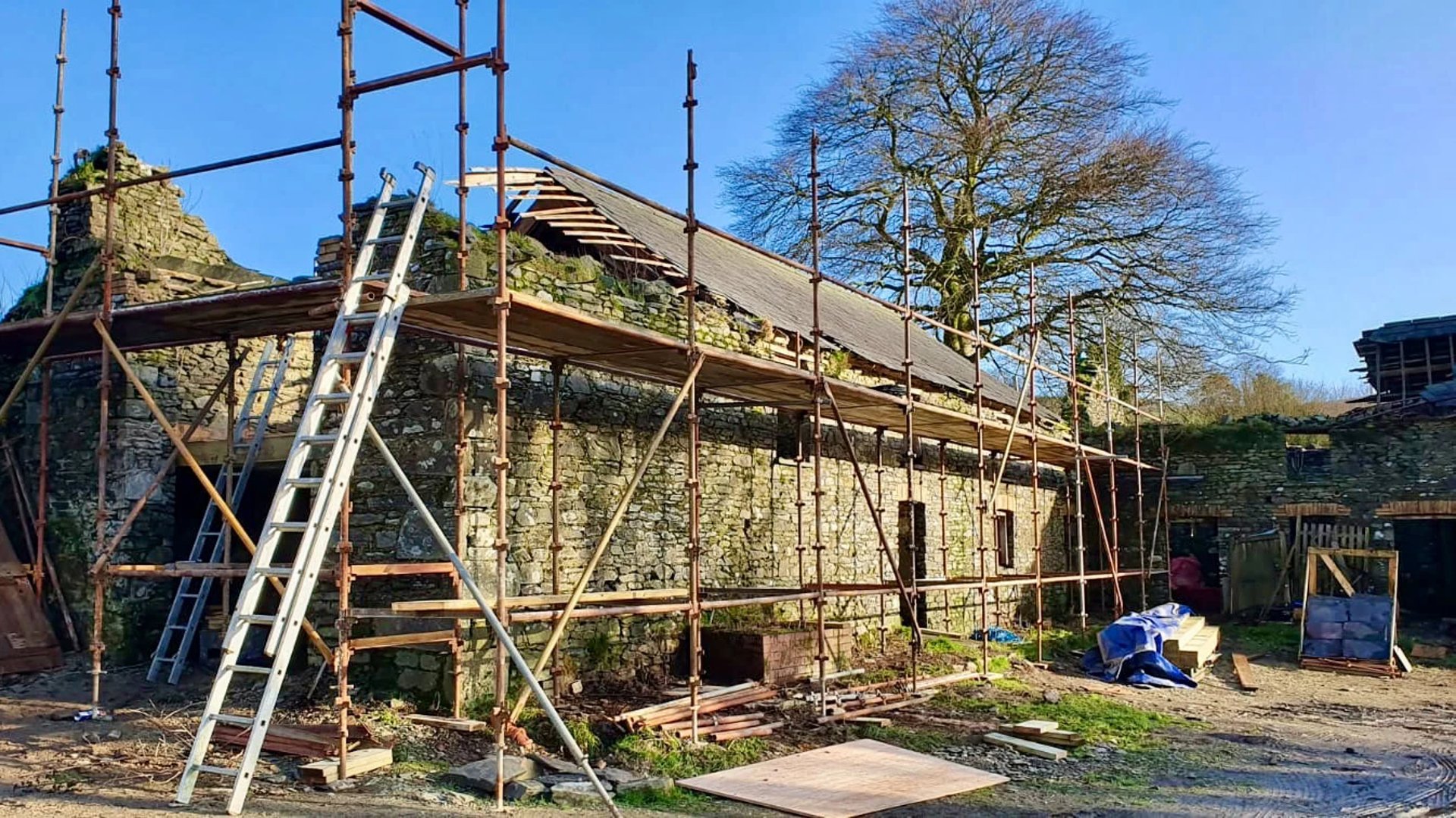 The barn during construction with scaffolding and ruined roof.