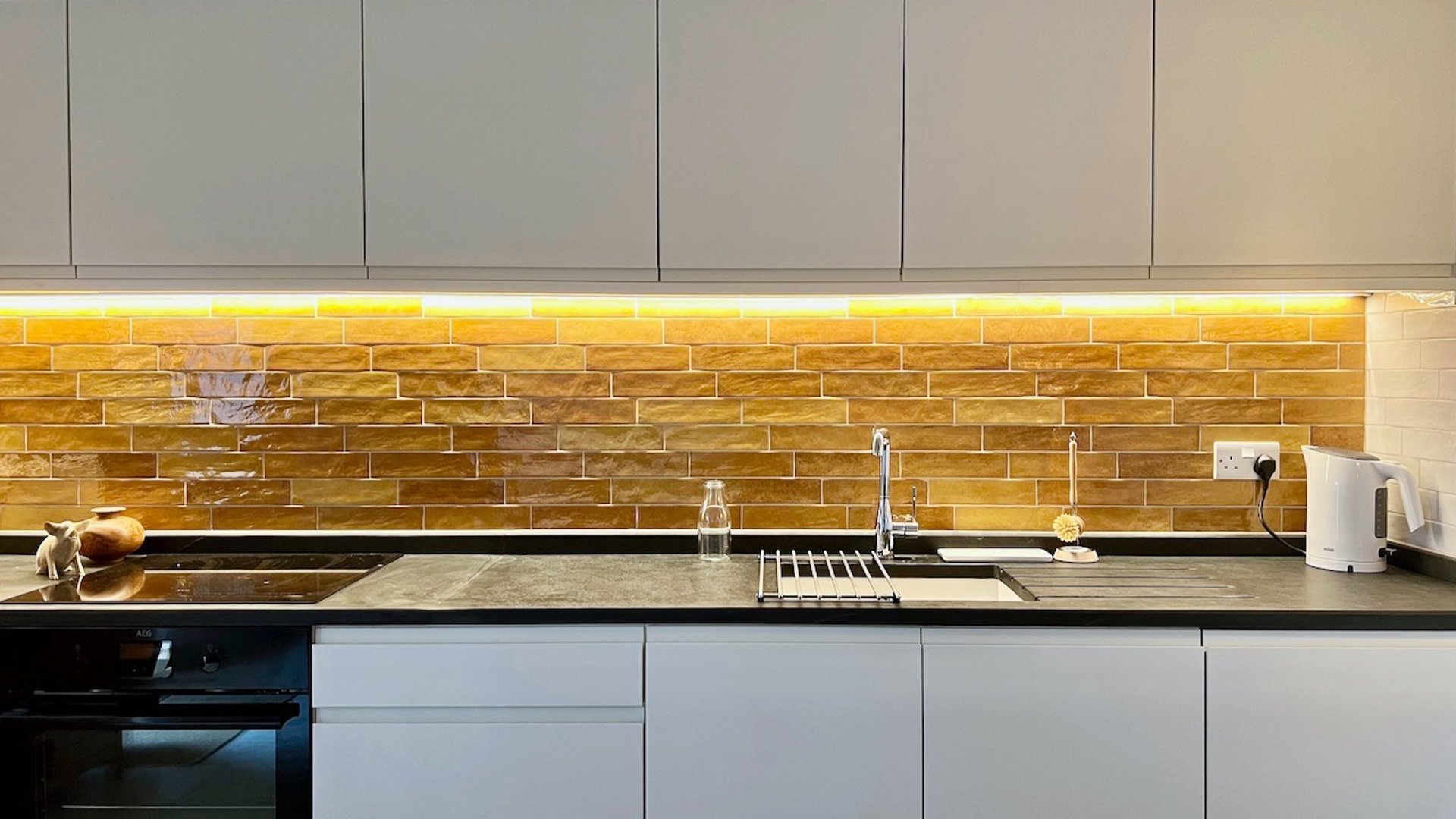 a range of kitchen units with slate worktop and colourful tiles