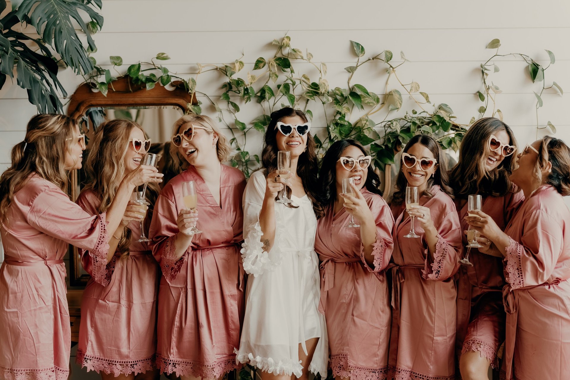 Bride with bridesmaids in matching robes and sunglasses celebrating with champagne before the wedding – captured by Anngye &