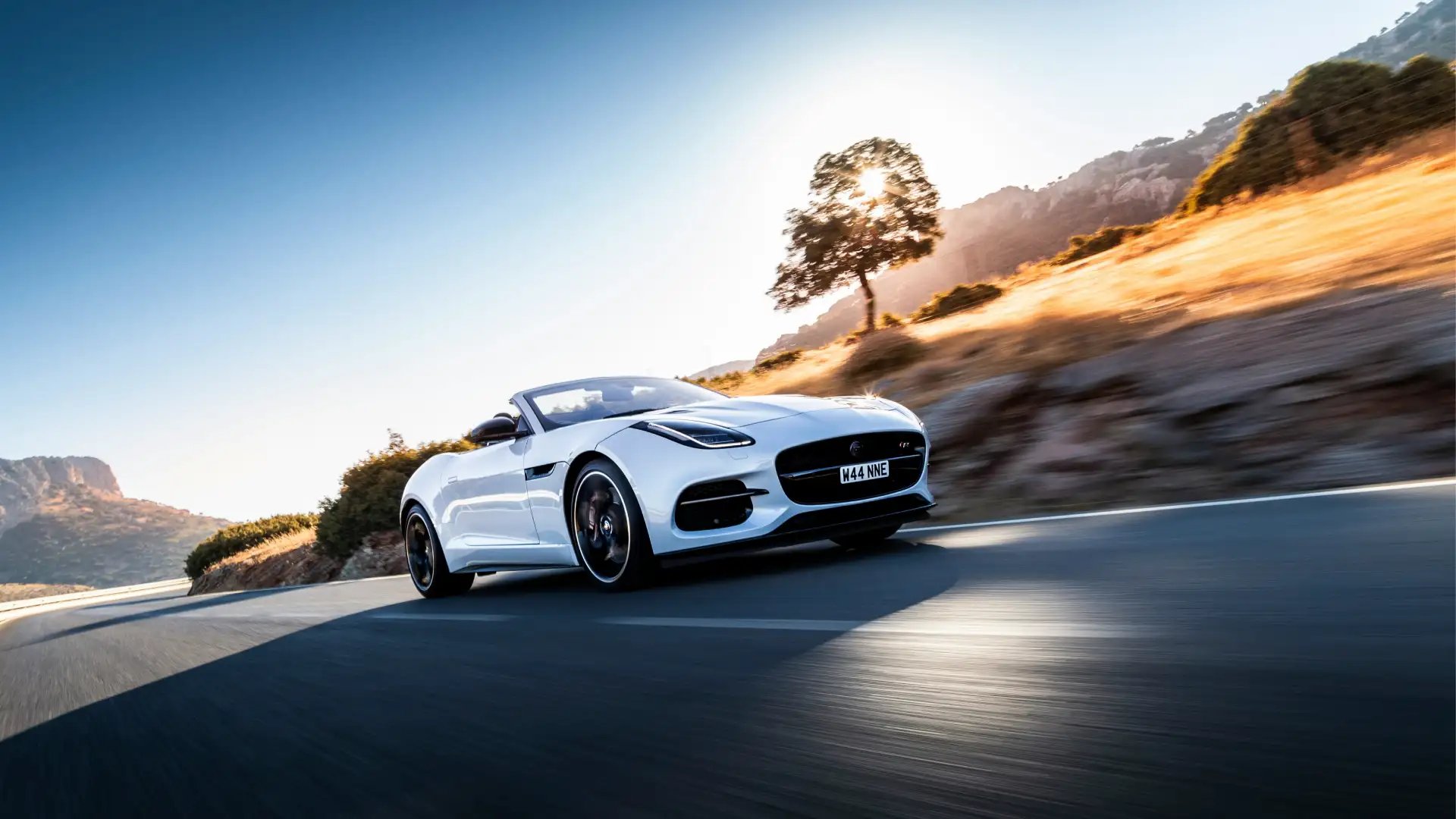A white sports car driving down a road