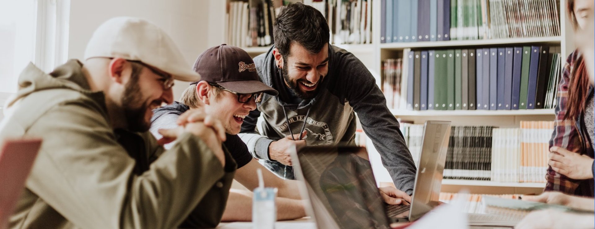 three men laughing while looking in the laptop inside room
