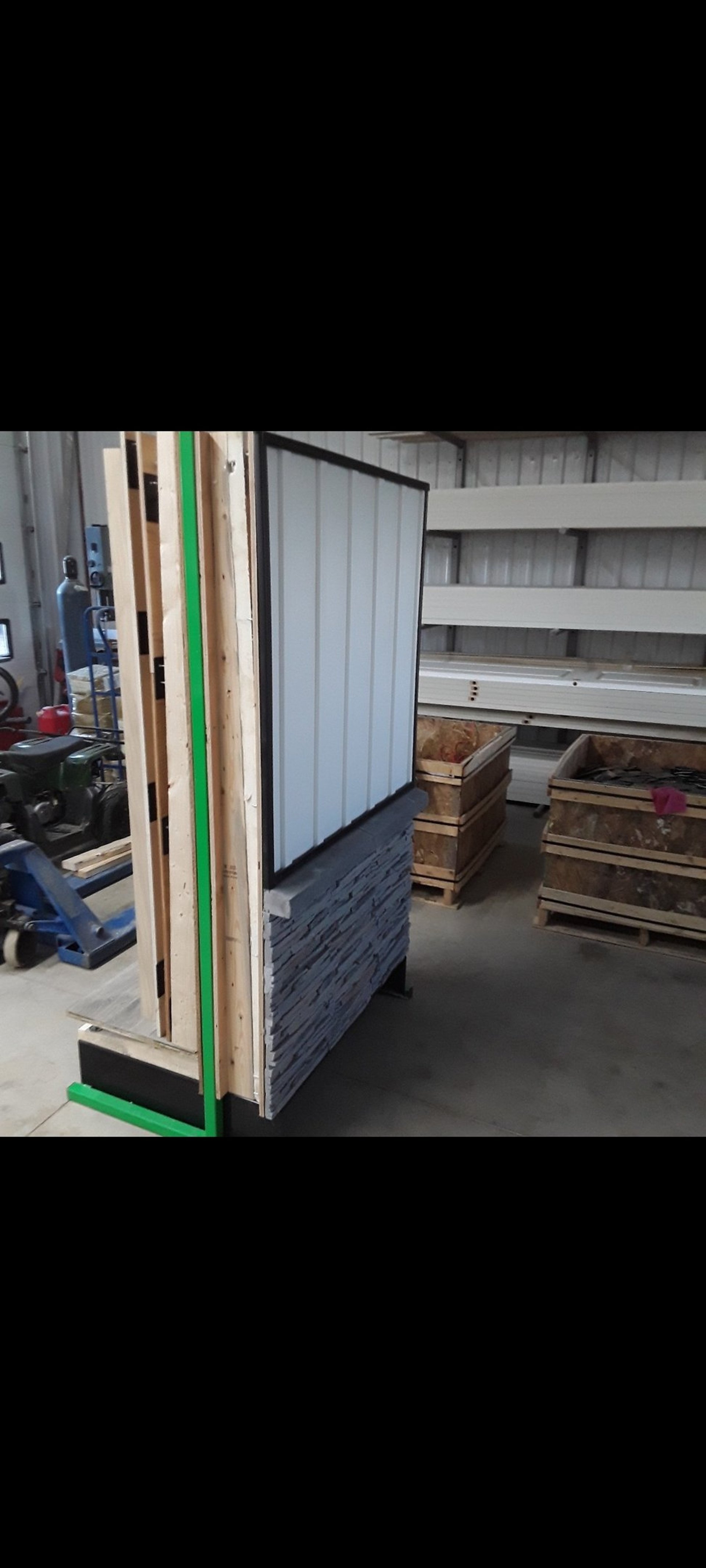 Wall assembly mock-up featuring stone veneer base and metal siding panel for exterior renovation demonstration