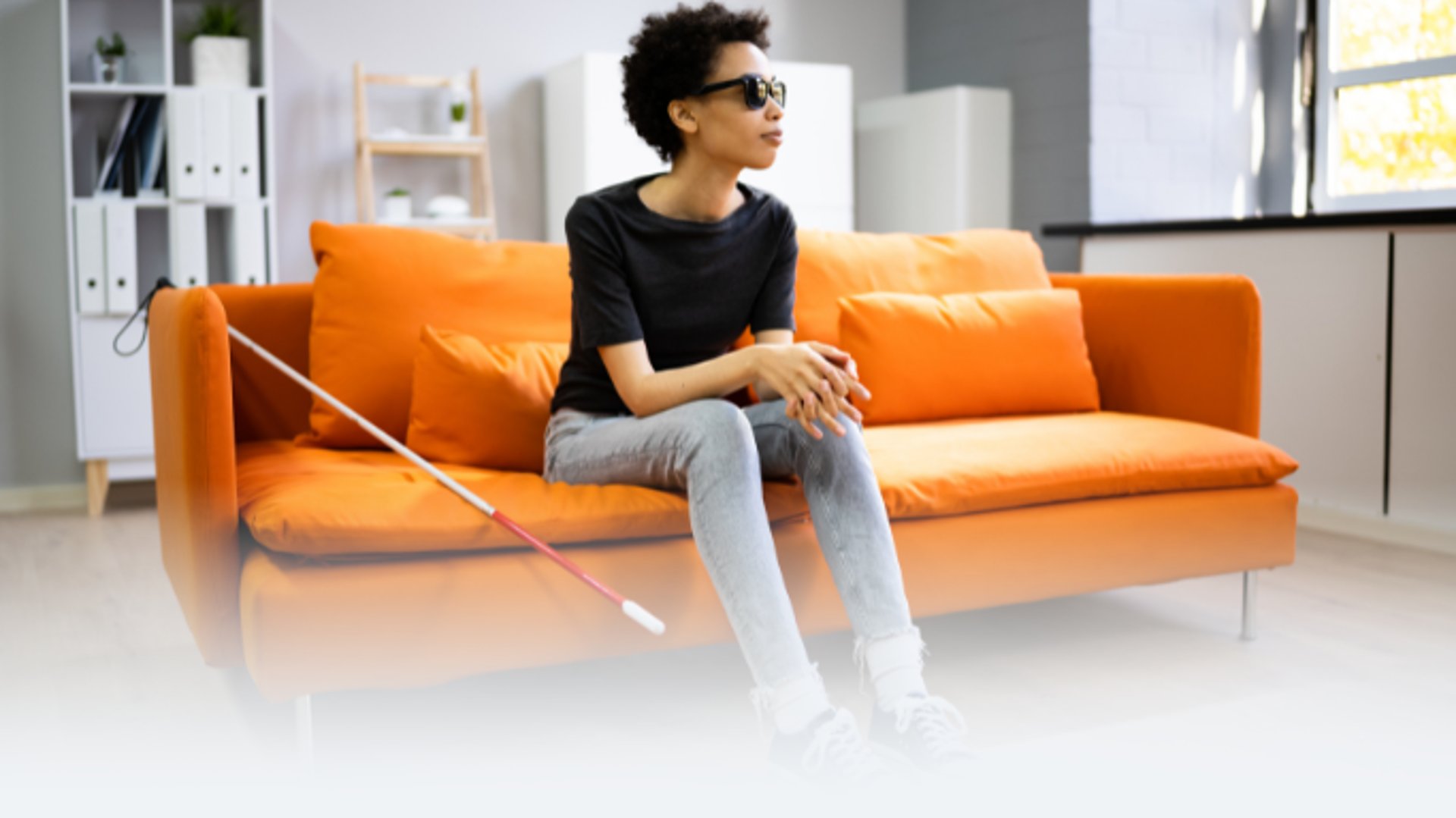 professional  woman with astigmatism blind  low vison woman with cane on orange couch wearing cocoon  glare shields