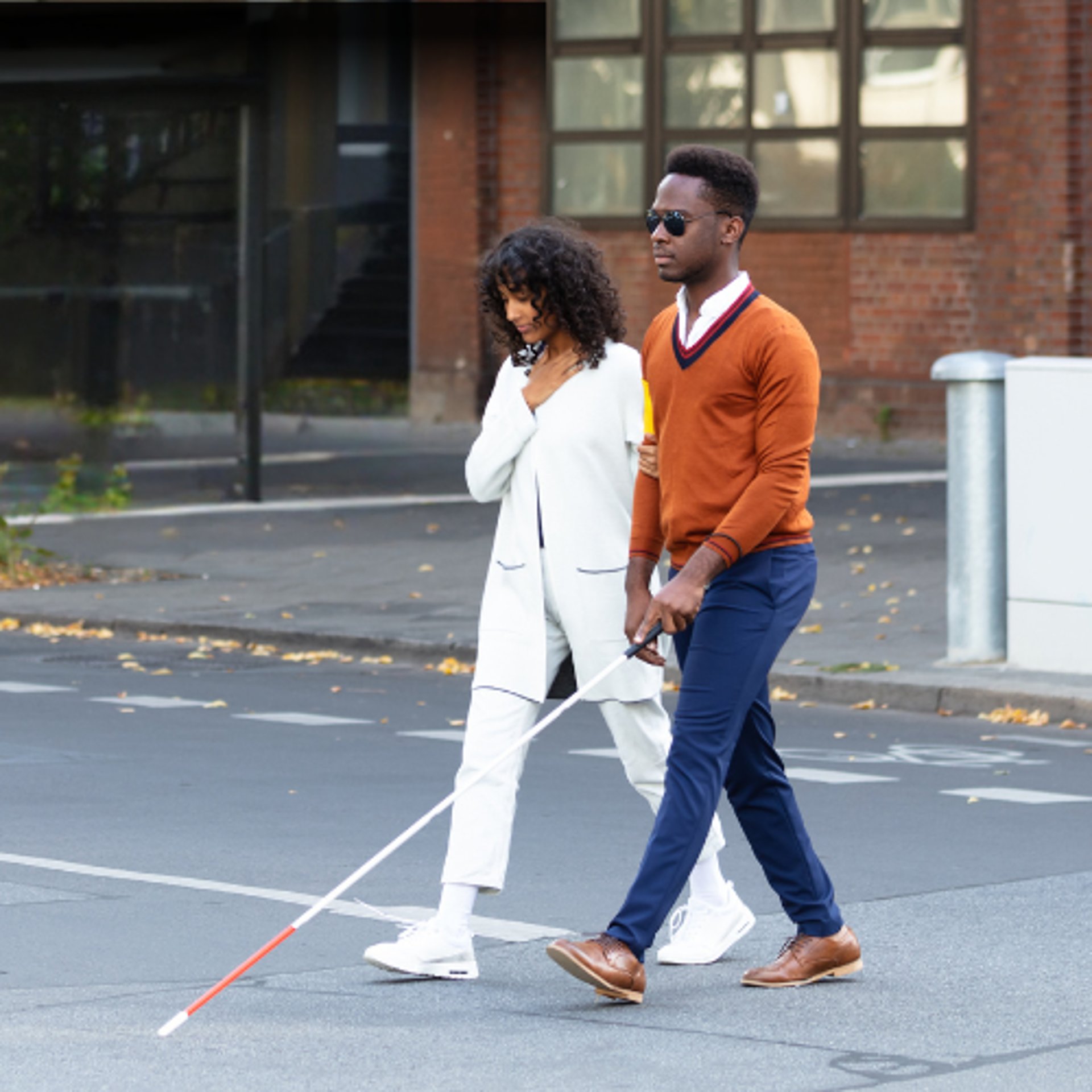 legally blind couple crossing street with white cane for the blind wearing glare shields for photophobia