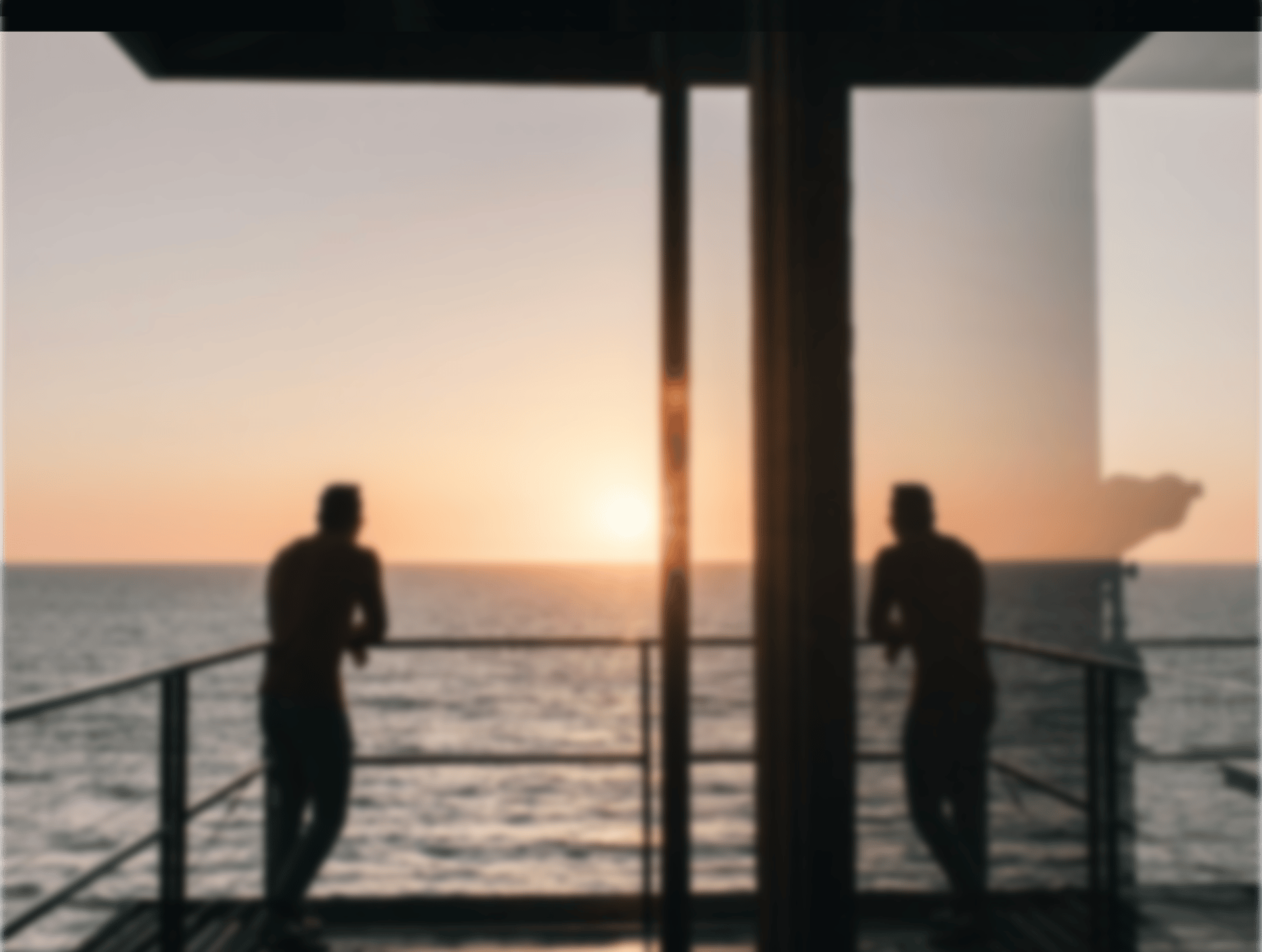 silhouette of man standing on gray stainless steel railing looking at sunset