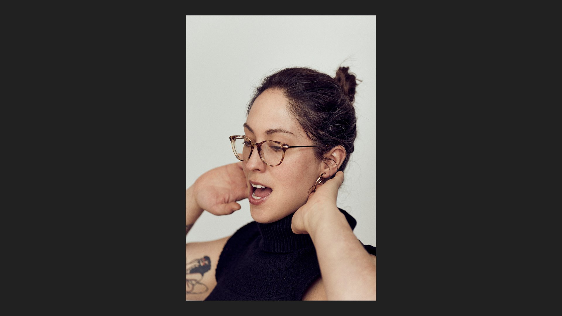 A headshot of a woman wearing glasses singing.